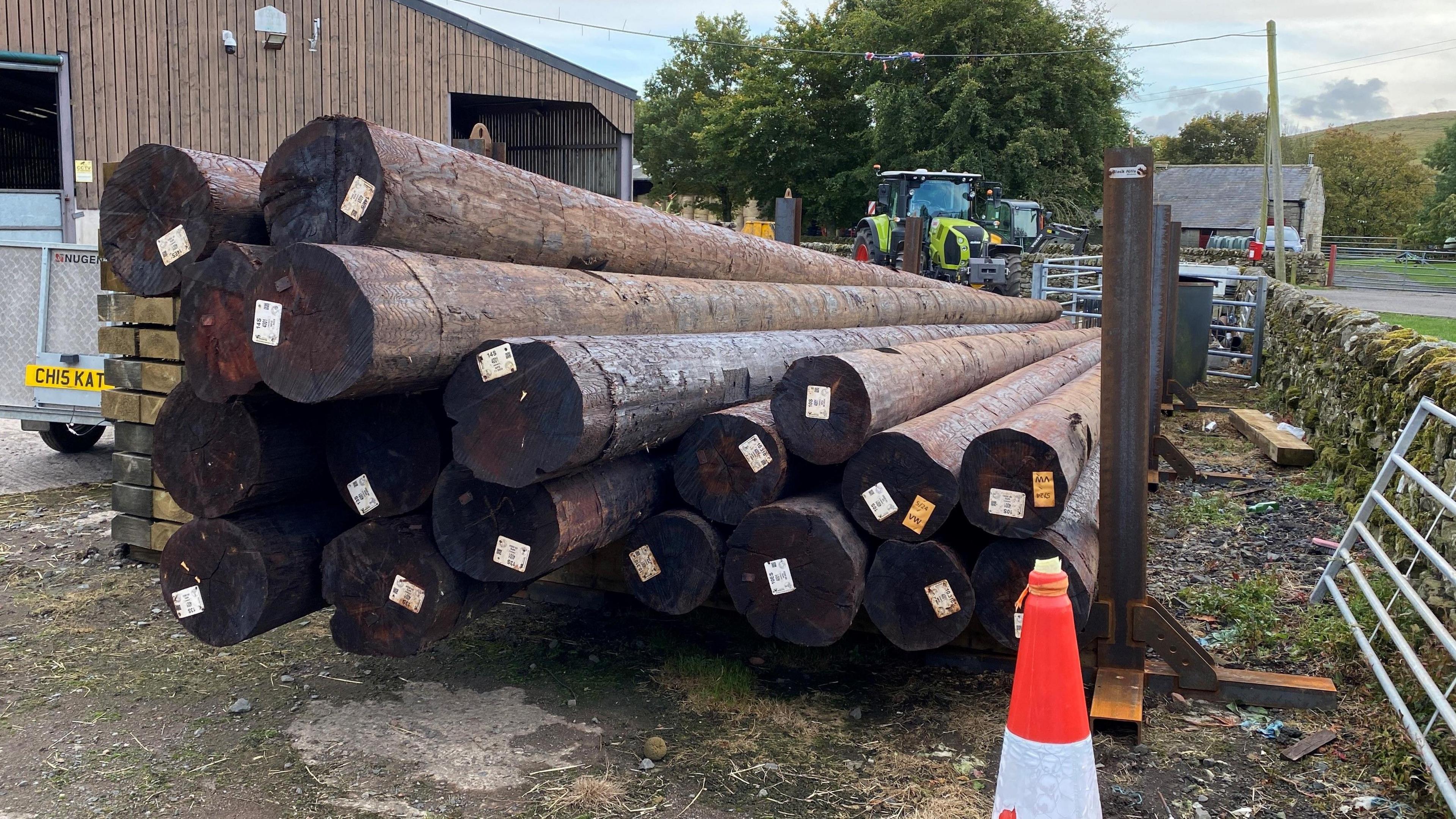 An image of a farmyard with lots of wooden electricity poles on the ground. 