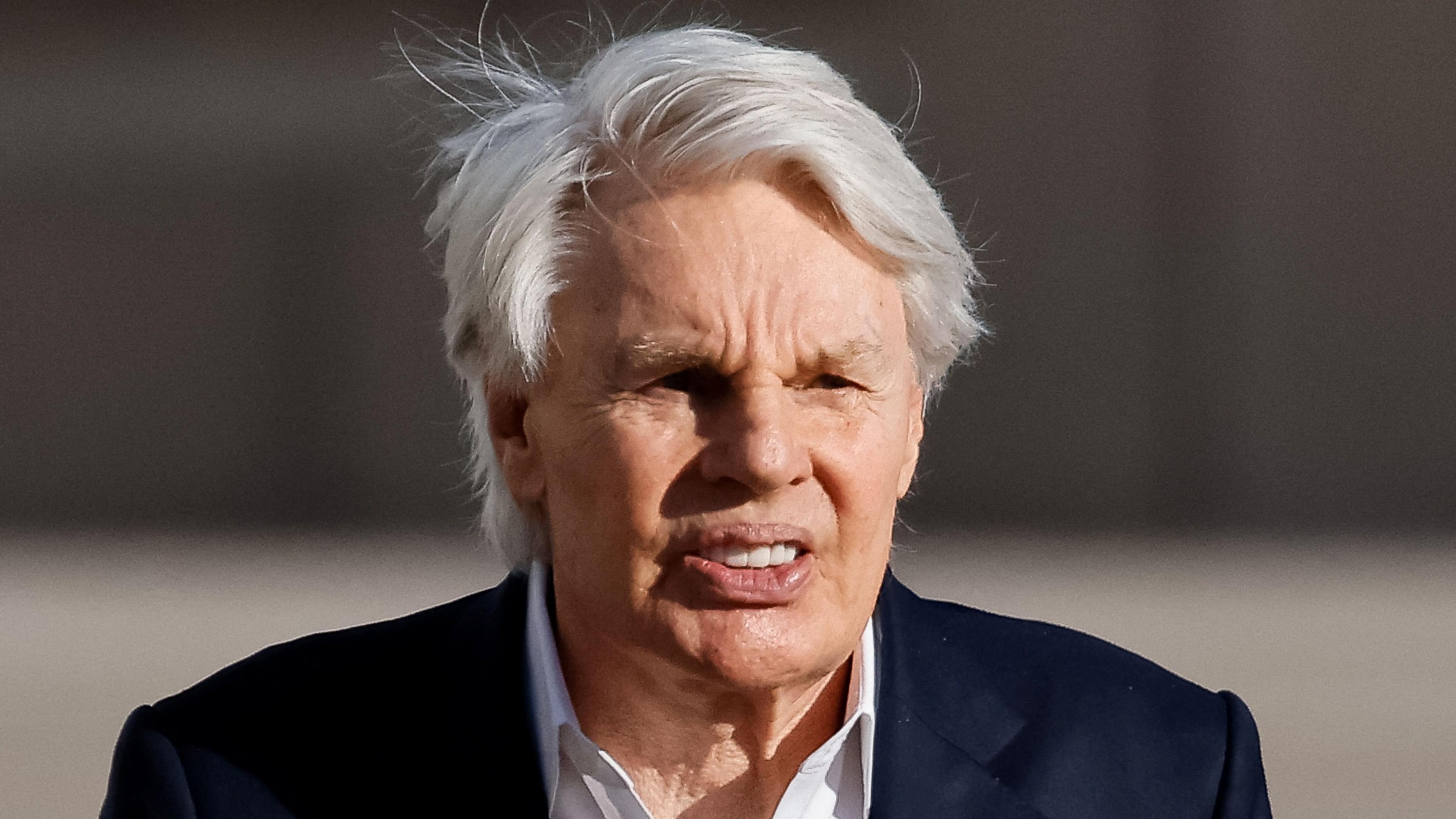 Mike Jeffries, an elderly man with white hair, wearing a dark suit and a white -open-necked shirt, photographed with a long lens outside the federal courthouse in Central Islip, New York, where he was arraigned on charges of sex trafficking and prostitution