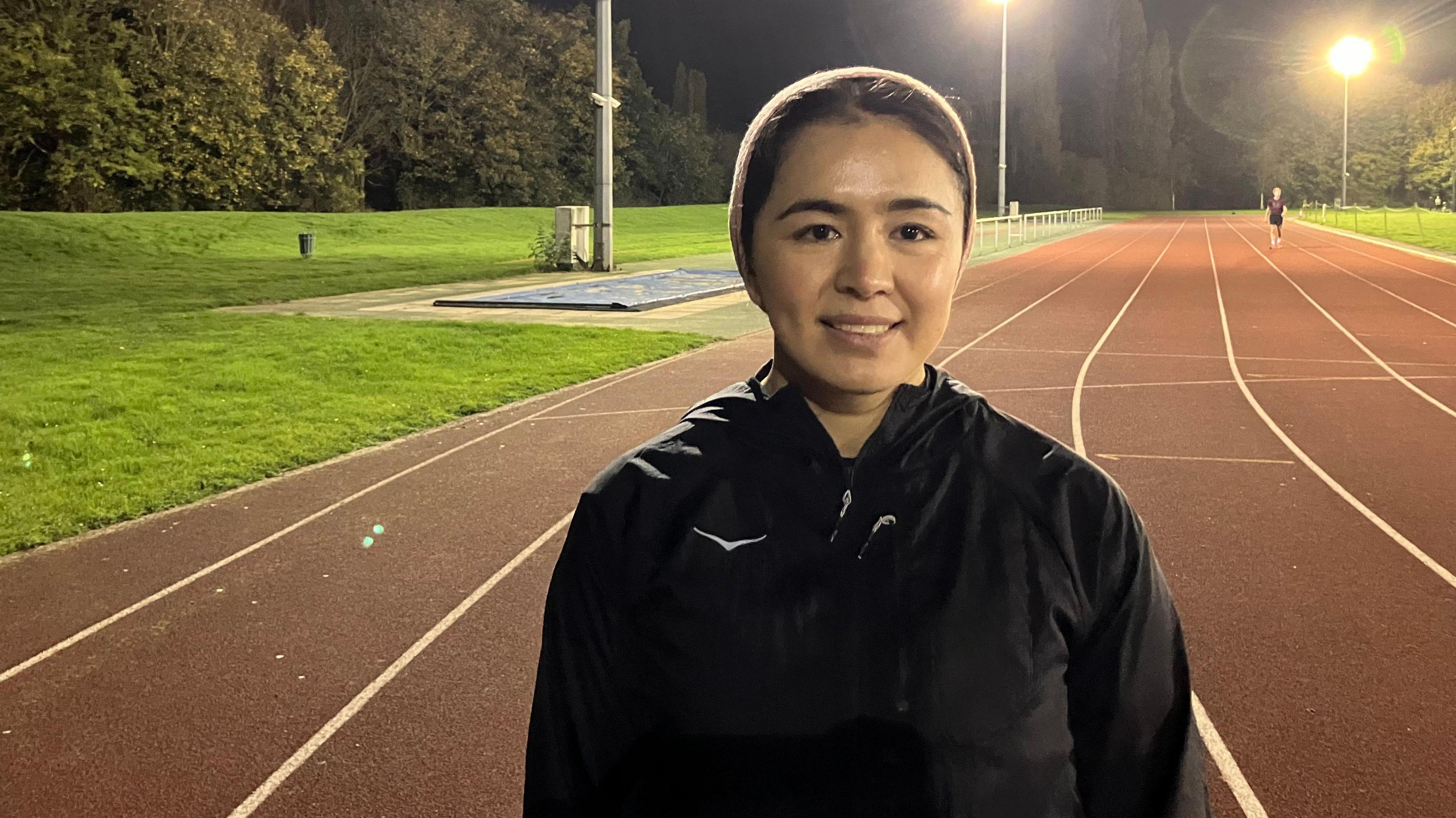 Fatima Painda wearing a black tracksuit jacket, standing on an athletics track 