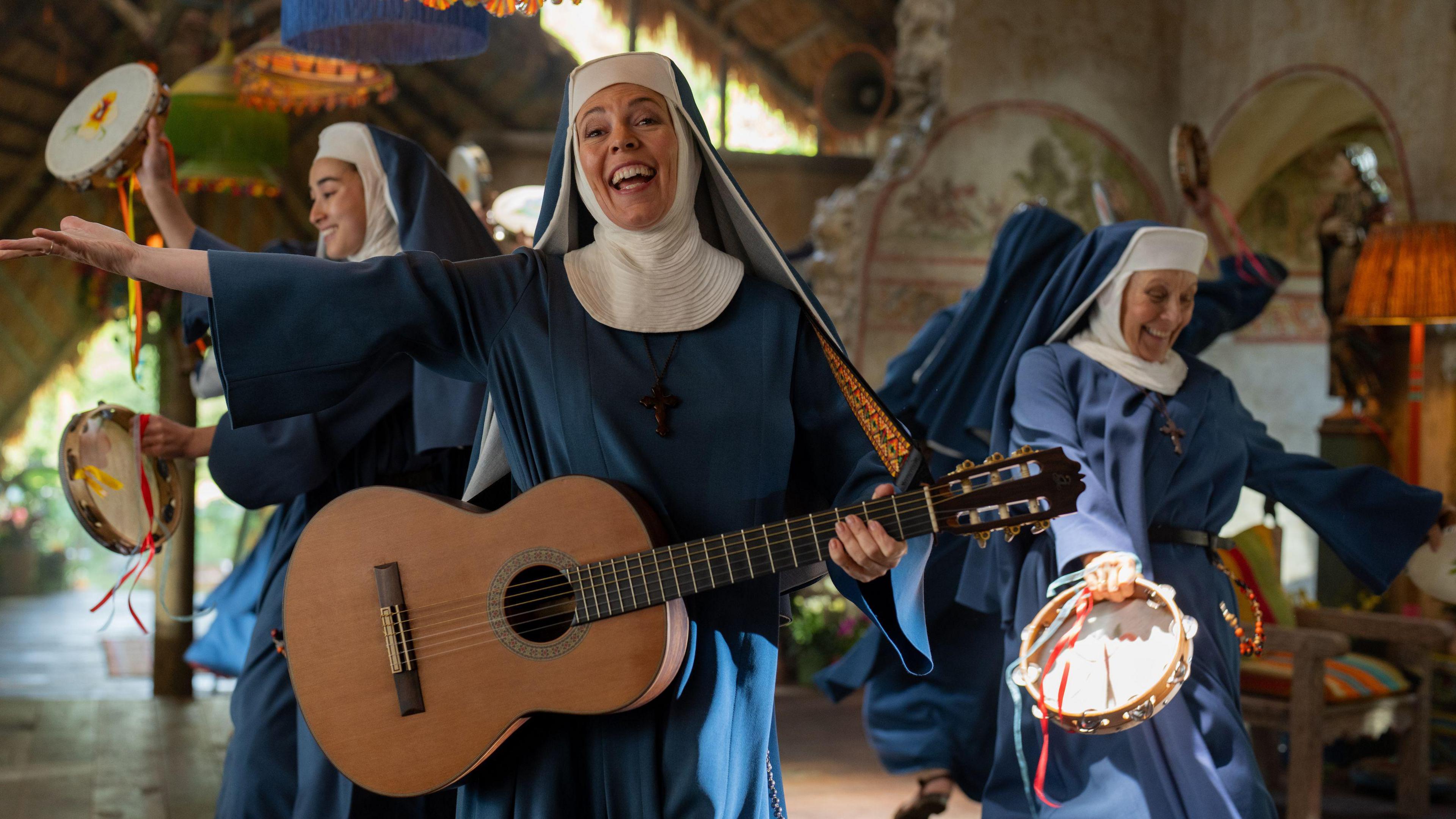 Olivia Coleman in Paddington in Peru dressed as a nun holding a guitar