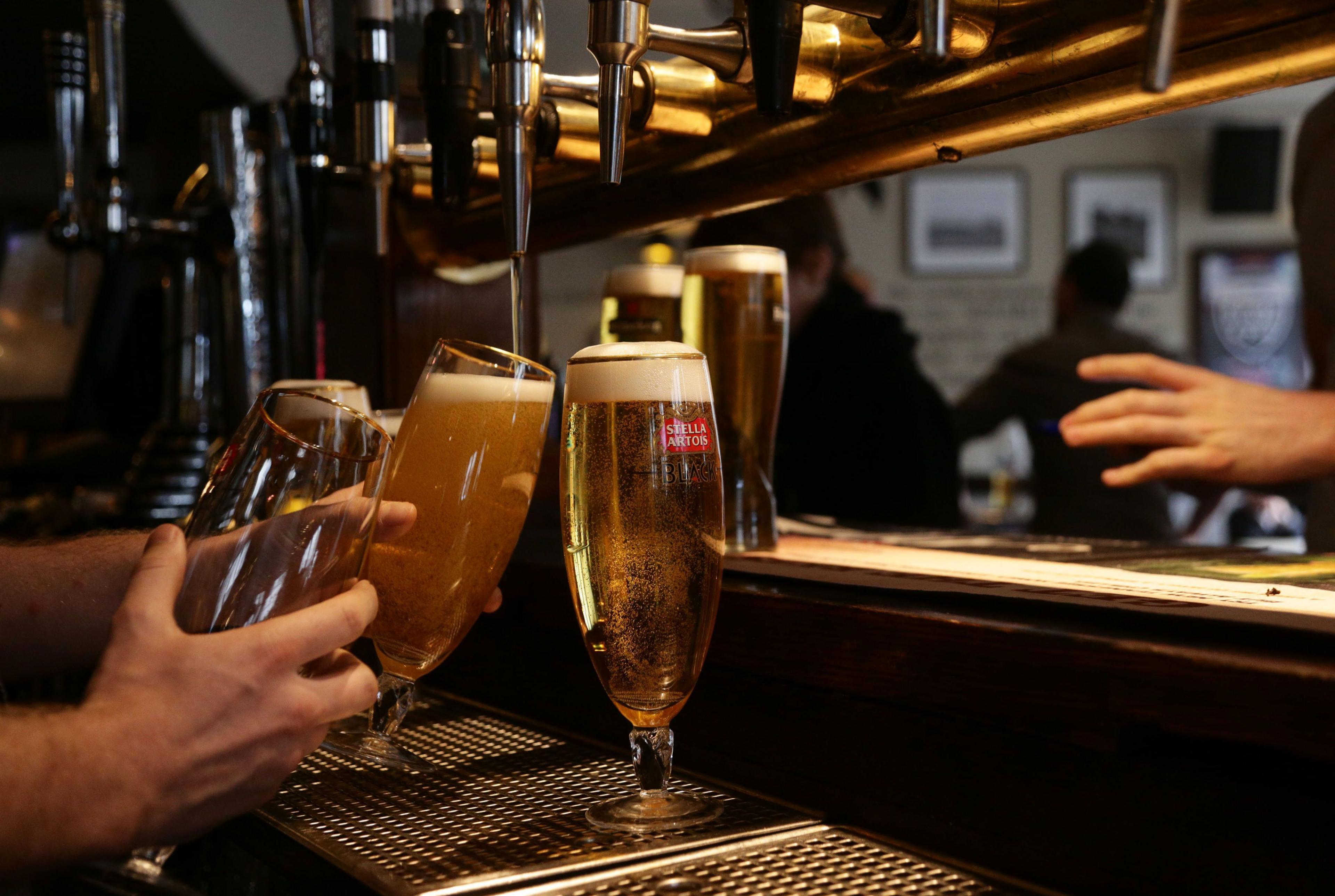 Close up shot showing a man's hand pulling pulling two pints of beer - one is already full with a head of froth, the other is almost full beneath the tap