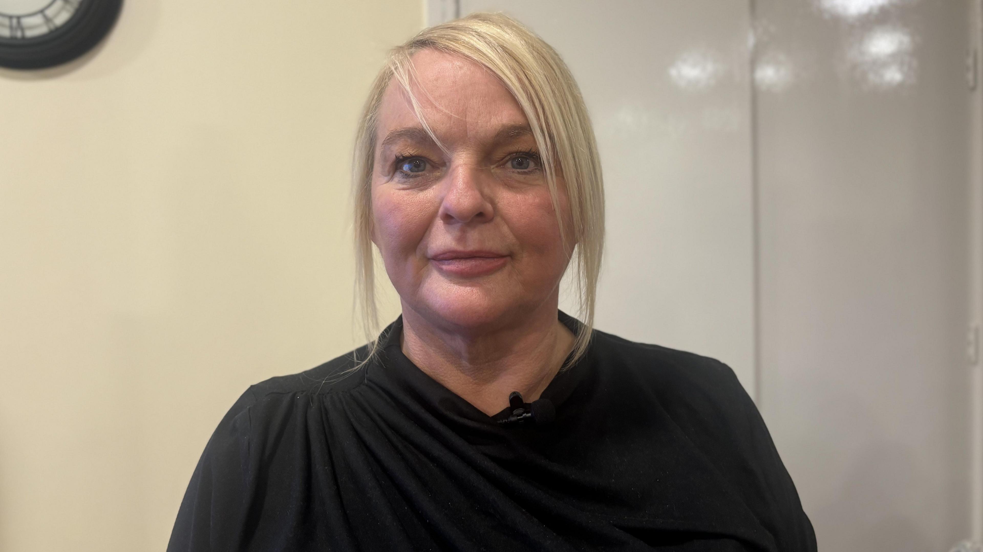 Head and shoulder shot of Karen Noble who has blonde hair and is wearing a black top. 