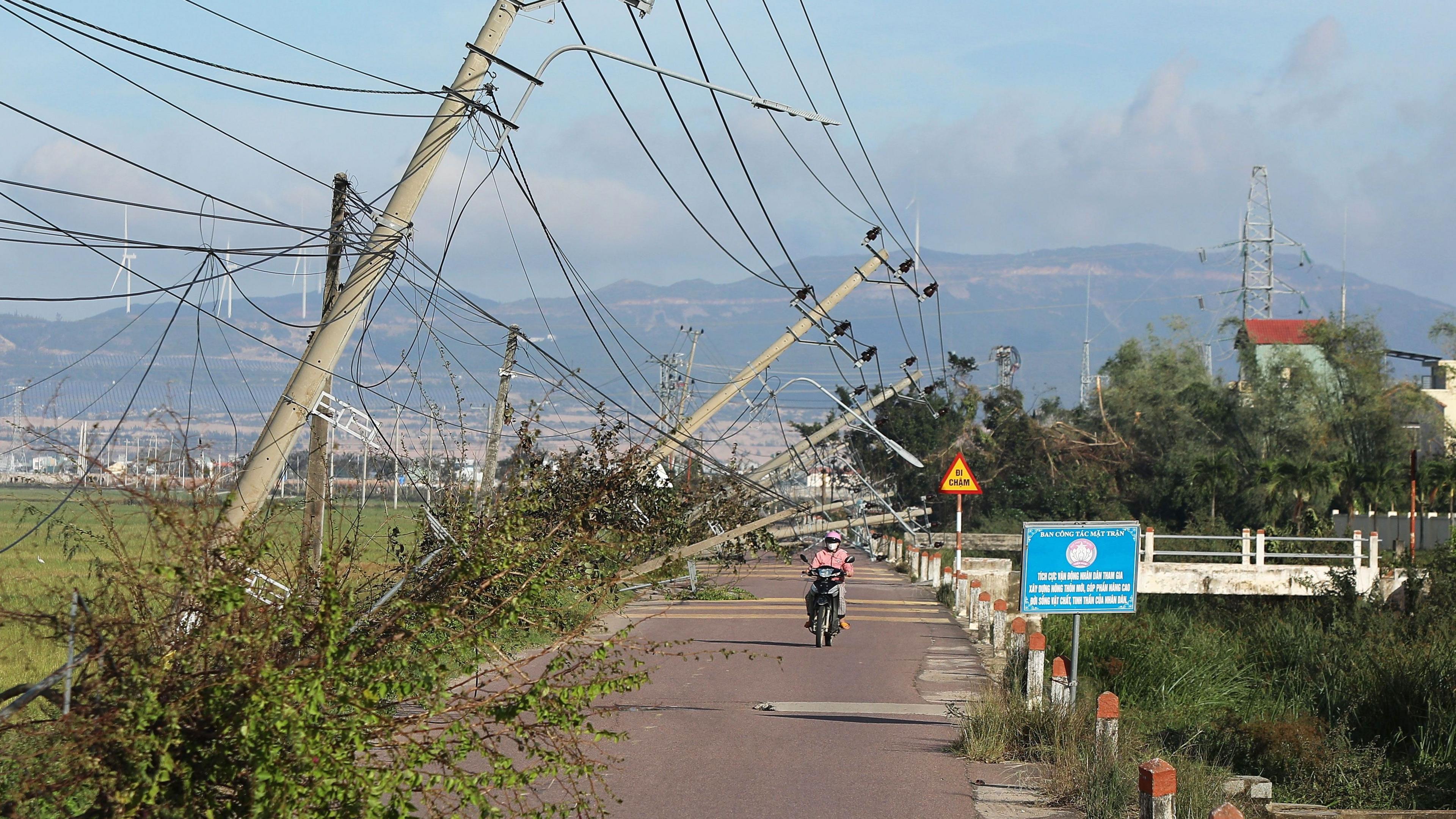 A man rides a motorbike in vietnam next to fallen electricity cables