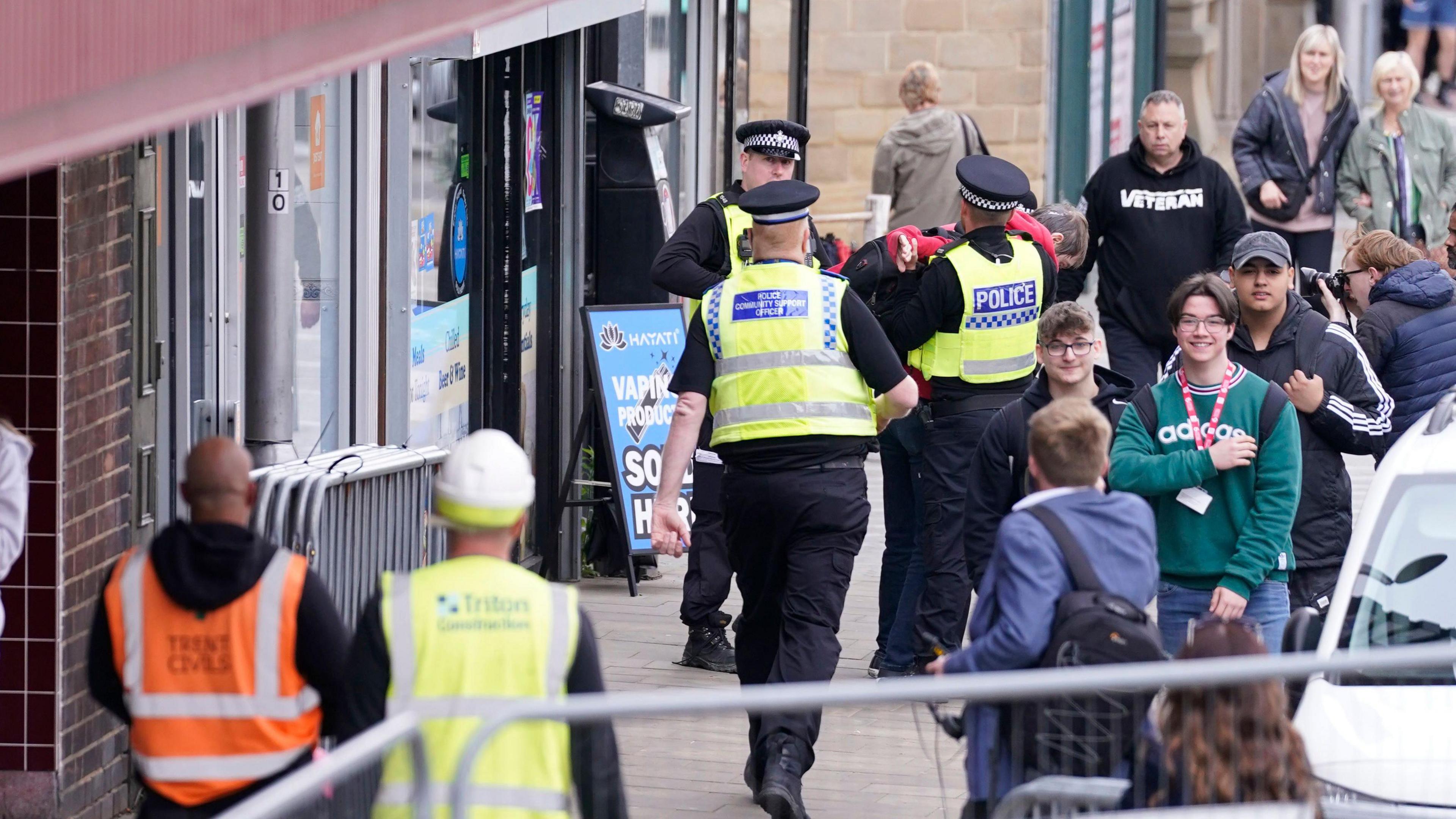 Police officers escort a person away