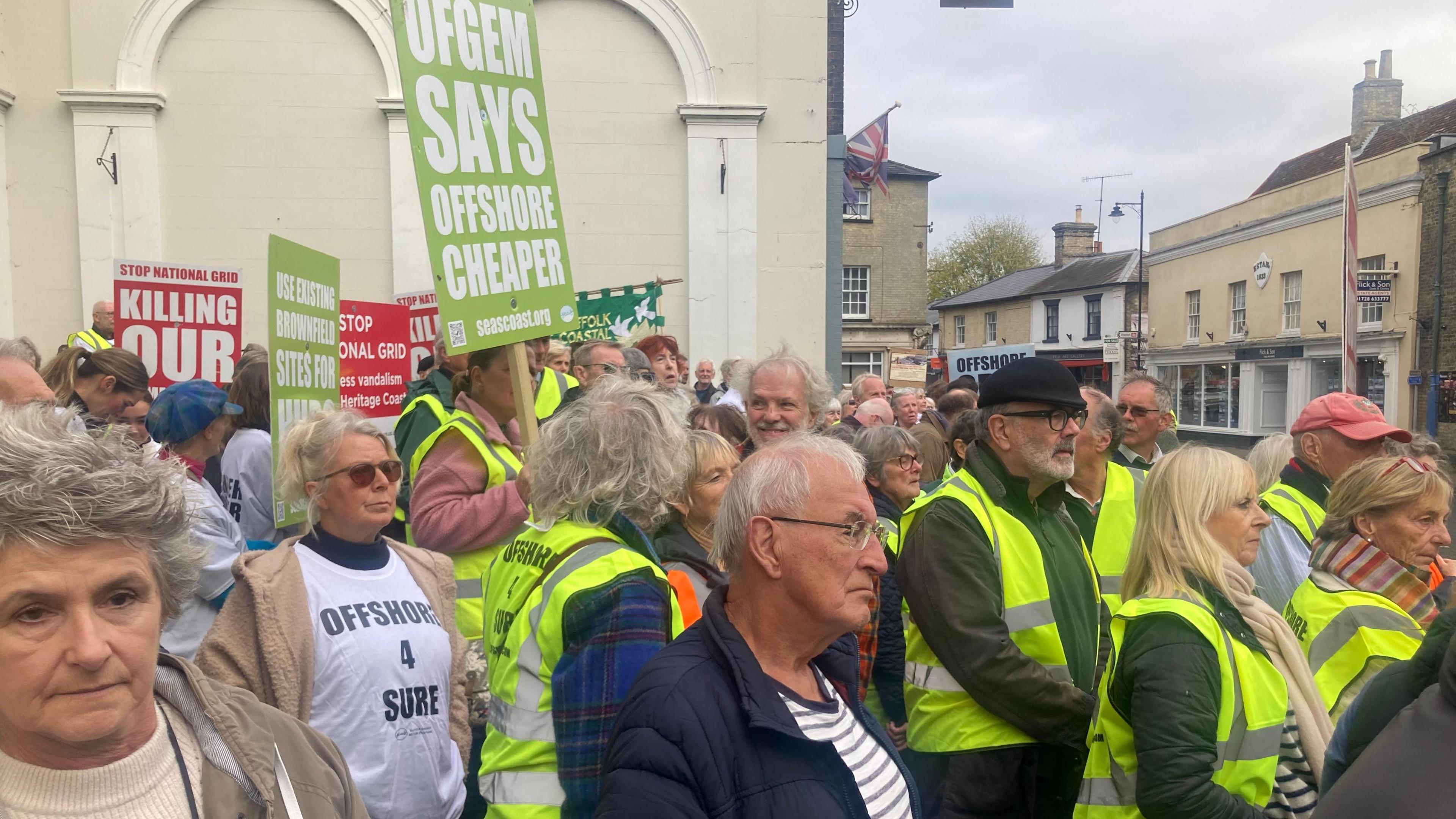 Protestors in the town centre holding placards. Many of them are wearing green hi-vis jackets