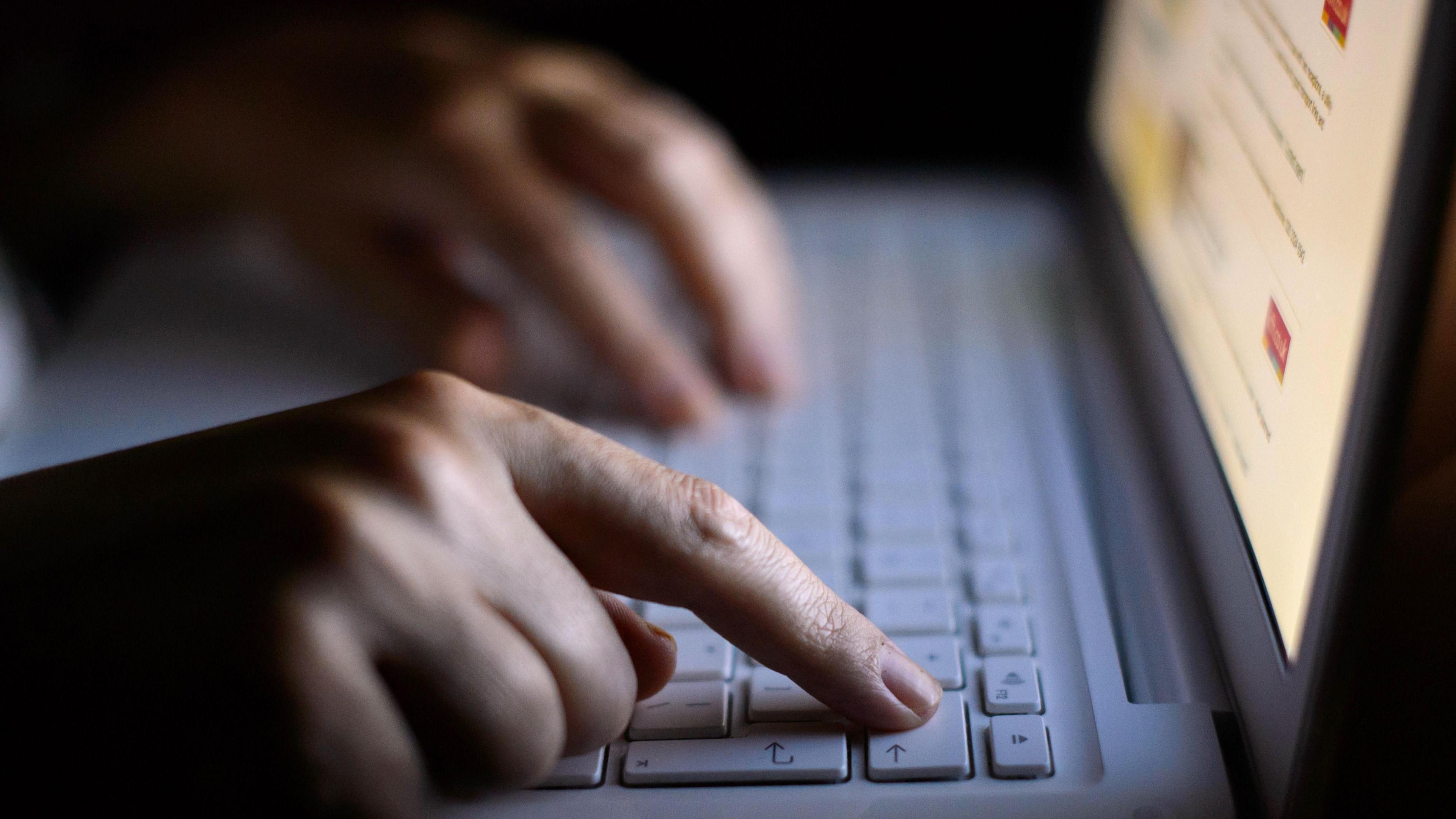 A person using a white laptop keyboard, with only hands in sight