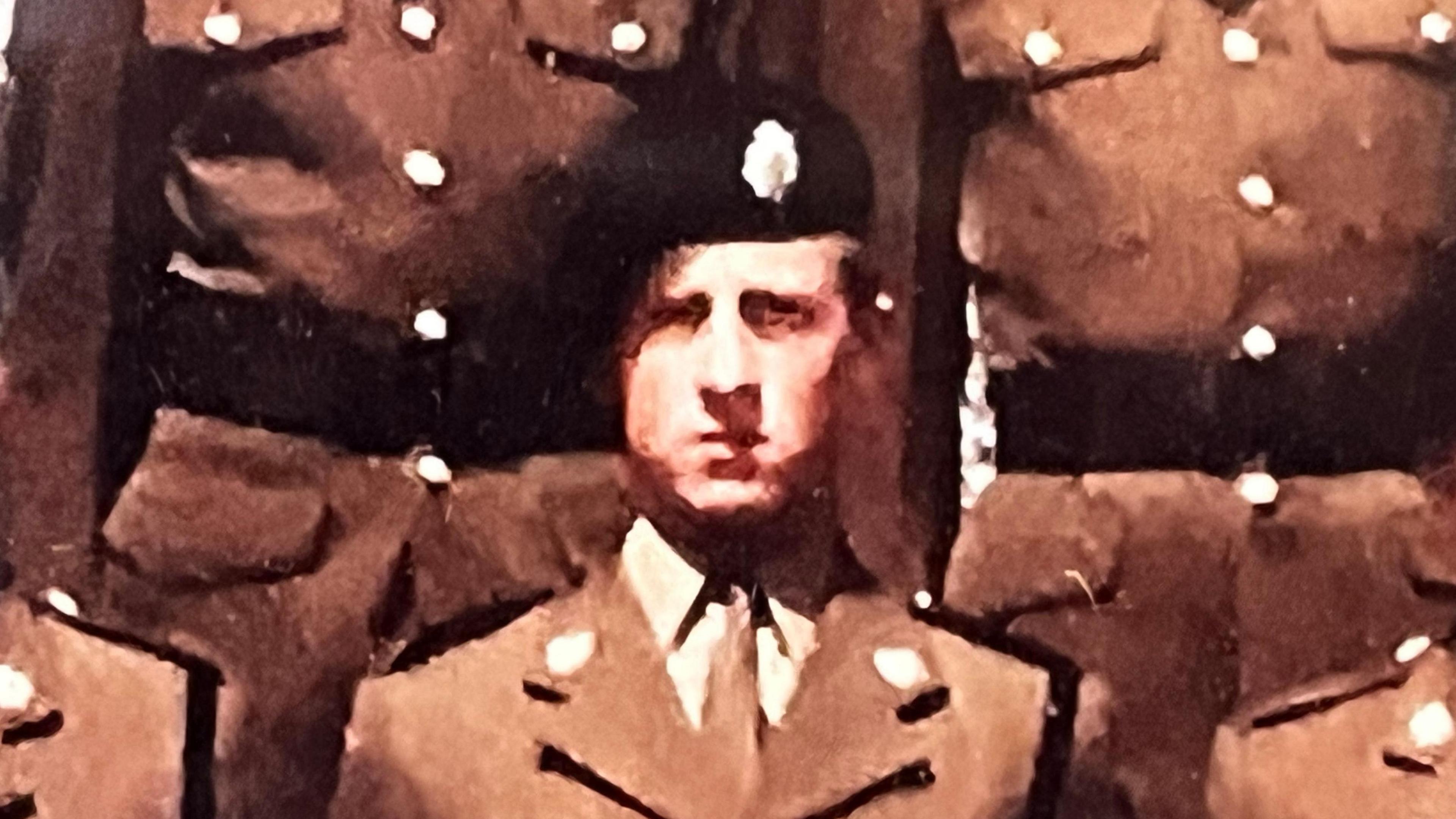 A slightly grainy photograph of a young man wearing a brown army uniform and a black beret with a silver badge on it. It's a formal photo, and Mr Tolhurst is standing shoulder to shoulder with other soldiers, but their faces are cropped out. 
