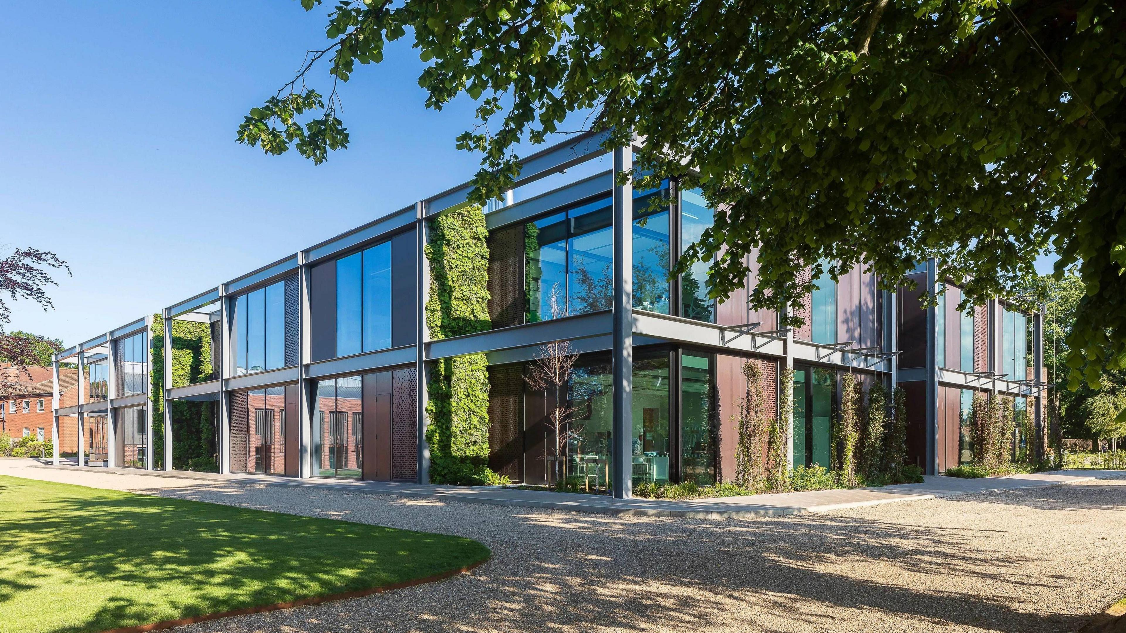 A modern industrial-looking two-storey building, which has a mixture of large windows, copper cladding and protruding steal beams on its exterior.