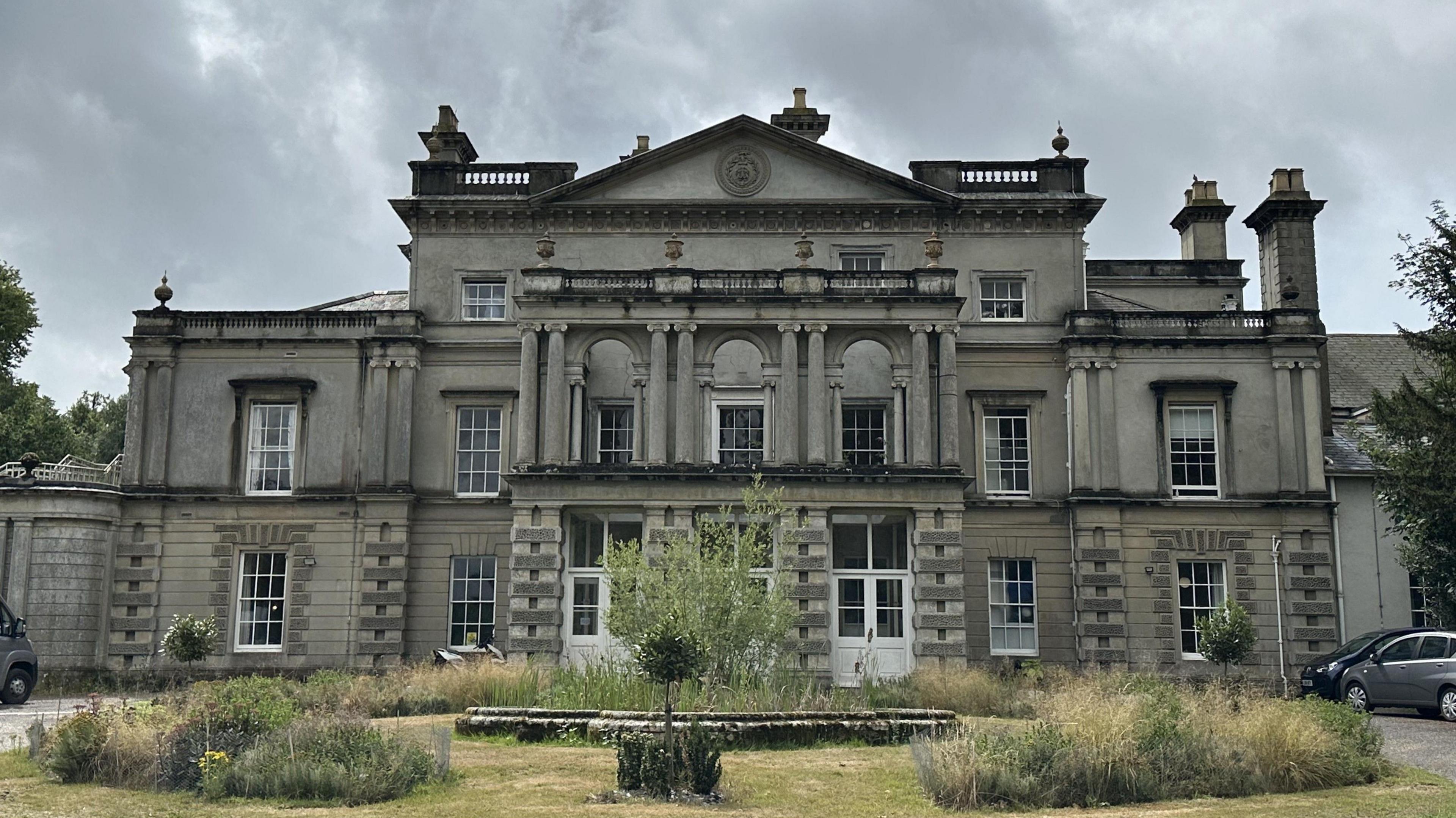 A large mansion-style home is pictured which is the home of Brainkind. A grassed area sits in front of the house.