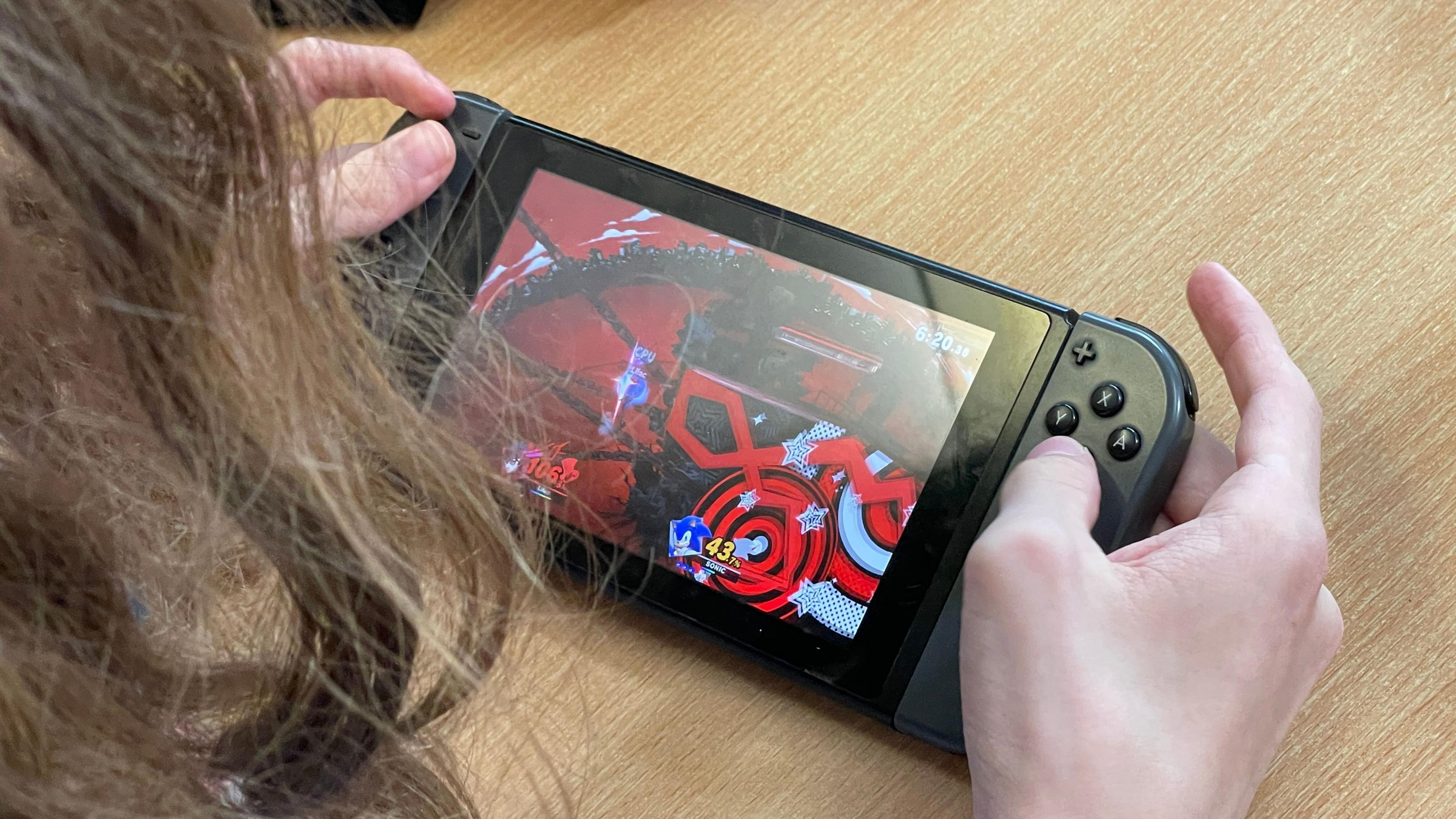 A student is holding an all-black Switch in his hands and looking down at the screen. They are playing a Sonic the Hedgehog game.