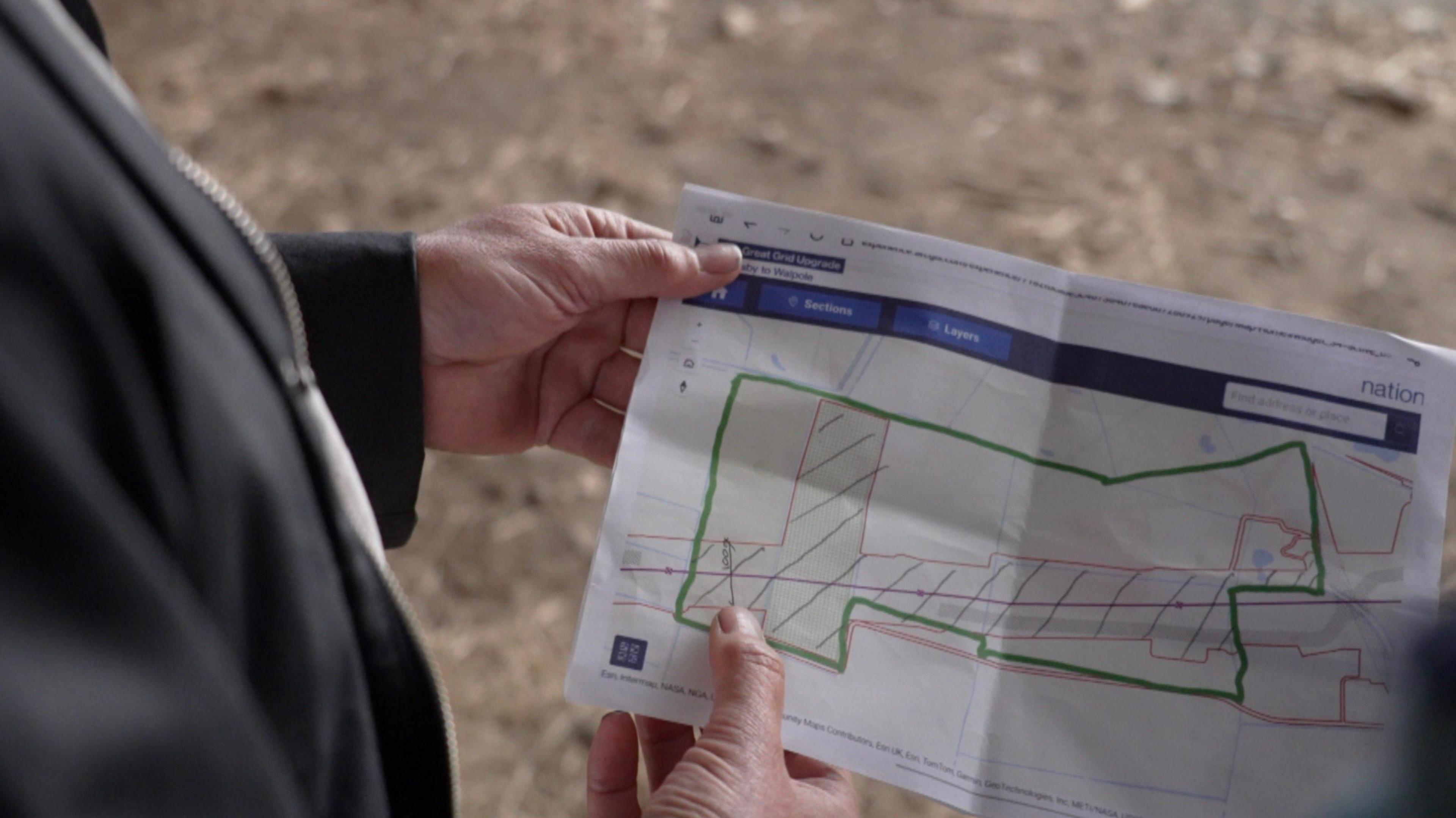 Jon Homer is holding a National Grid diagram which shows the company's proposal for his farm and the pylon route that will cross his land.