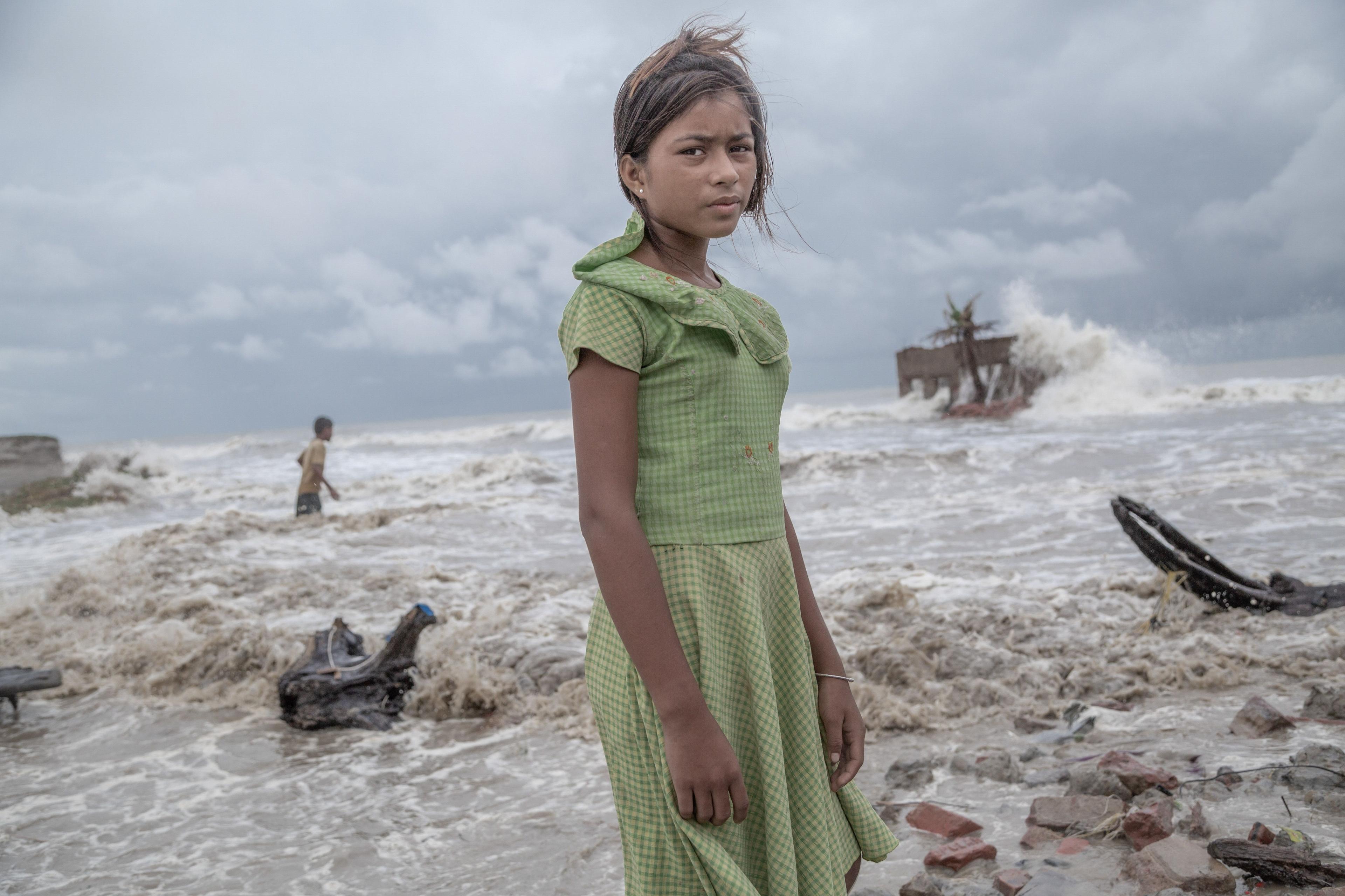 A girl stands in front of her tea shop, which has been destroyed by the sea during a storm, in Frazerganj, Sundarbans, India