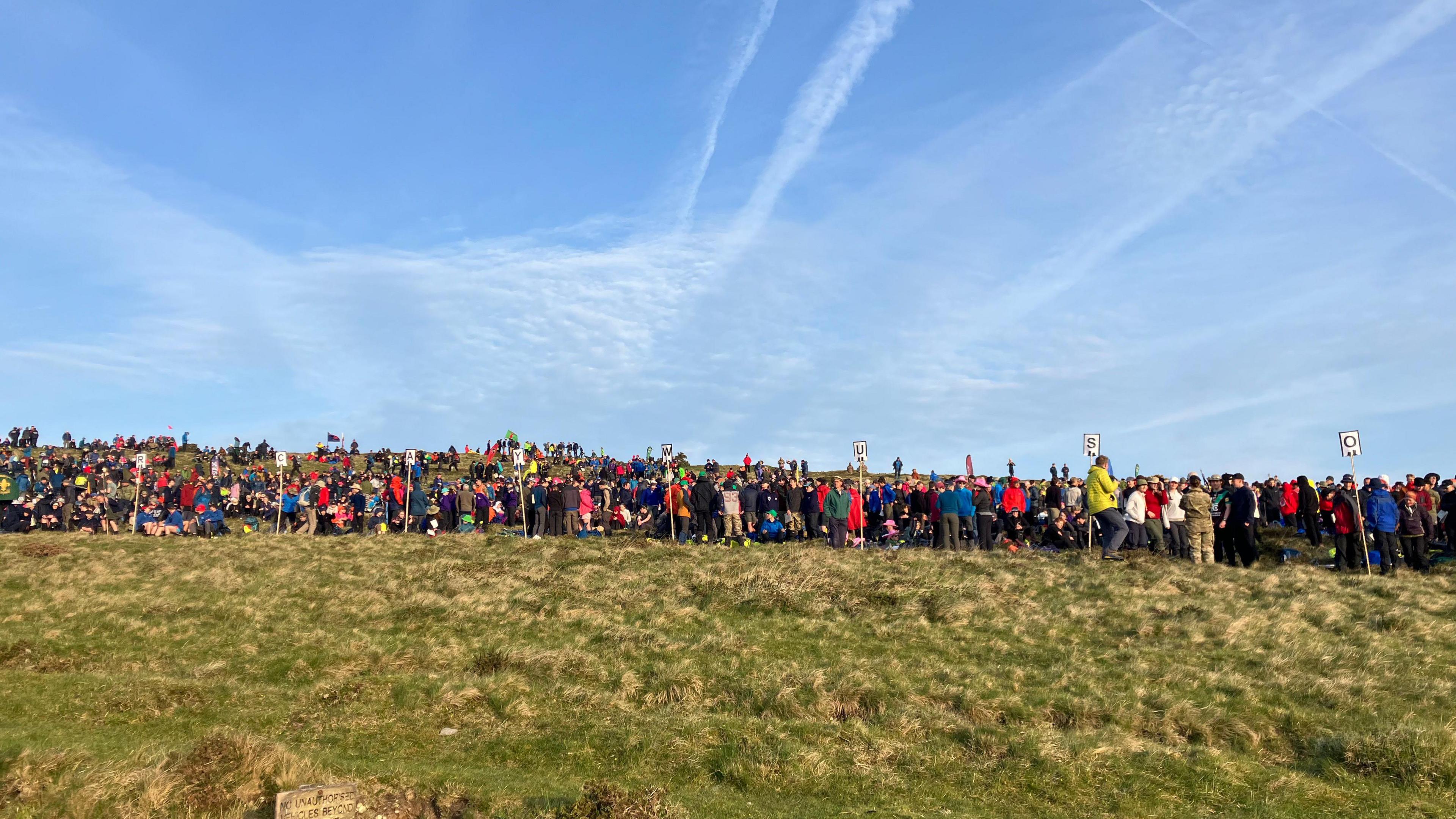 General view of participants setting off at Ten Tors in 2025. Hundreds of participants are stood in a long line on a grass field.