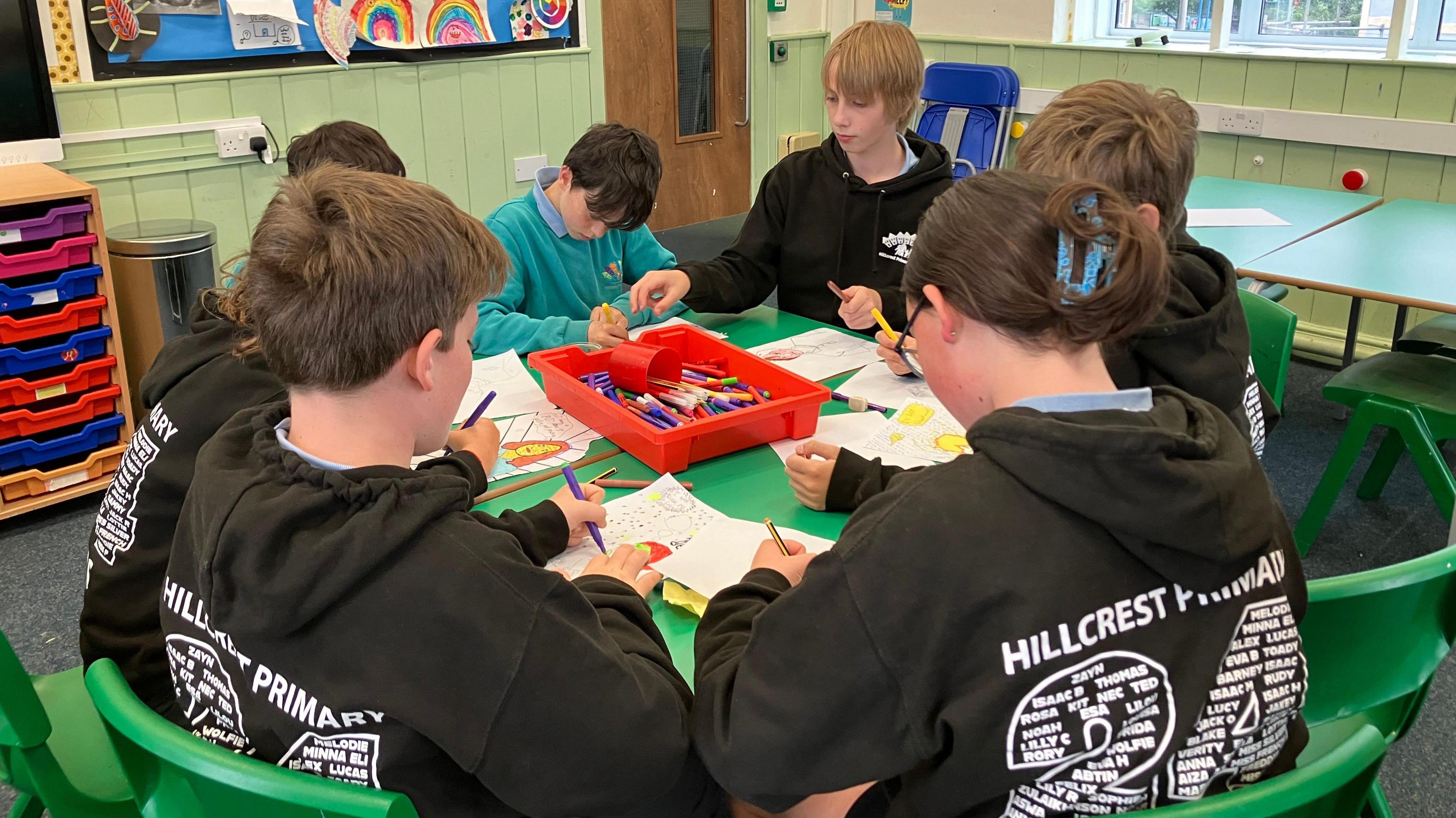 All of the twins sitting at a table doing some colouring in