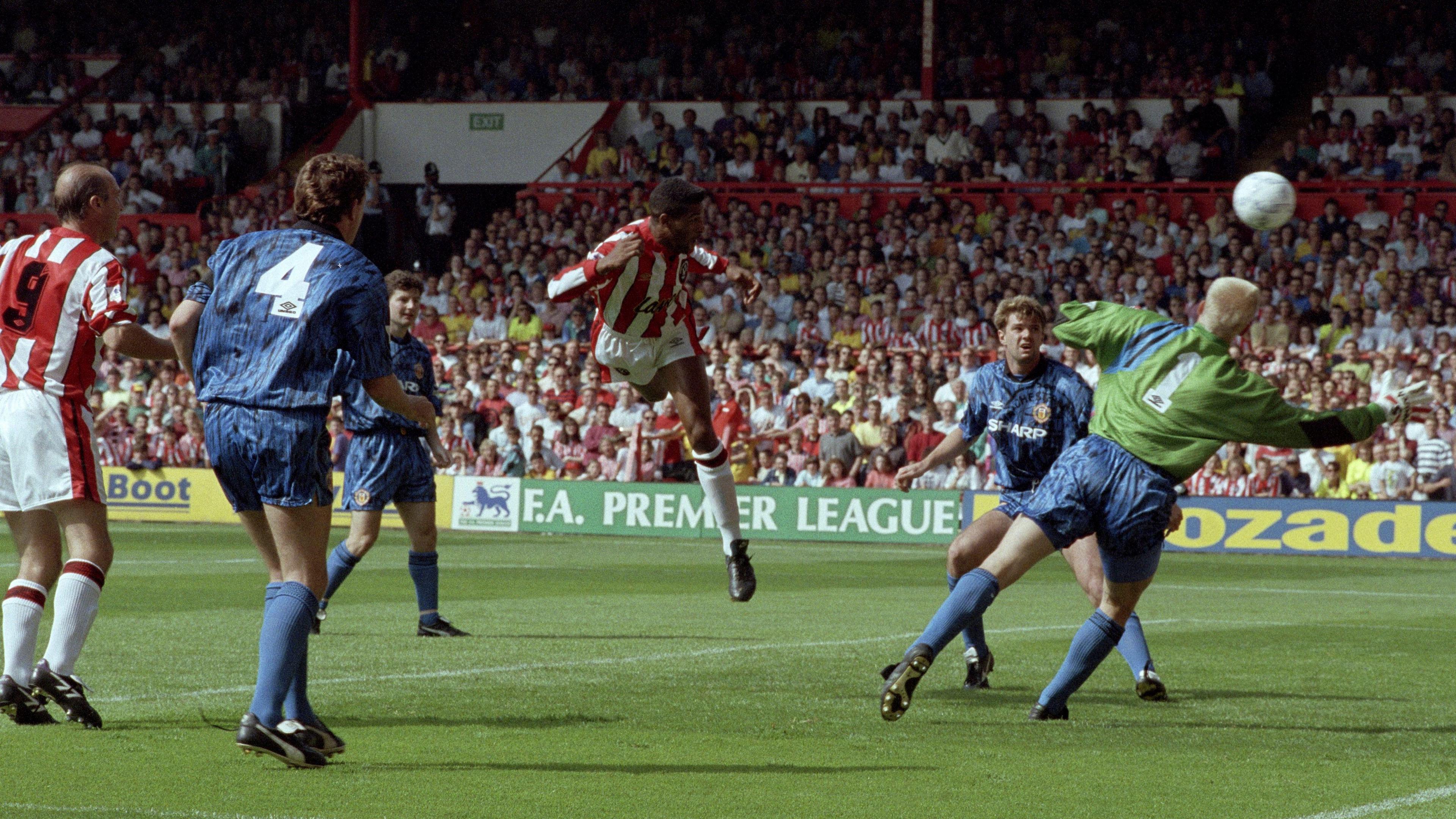 Brian Deane jumps to head the ball past Peter Schmeichel to score the first Premier League goal, for Sheffield United against Manchester United in 1992.