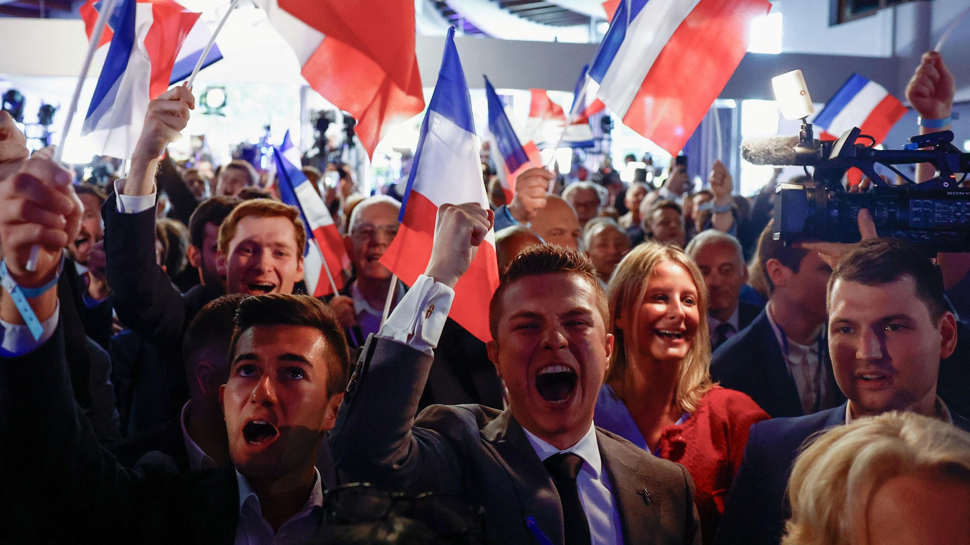 Young people dressed smartly wave French flags and cheer