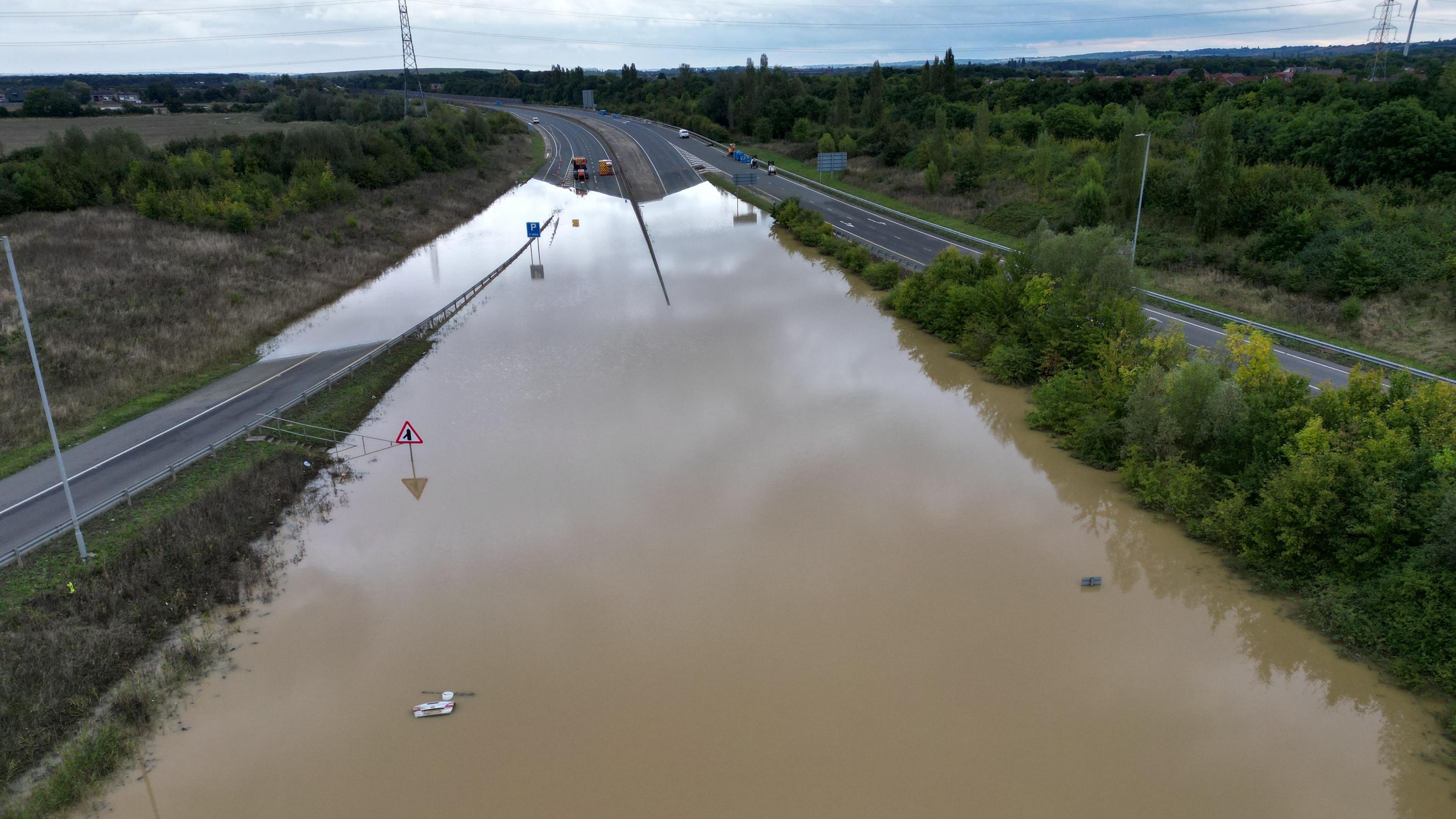 Murky brown water submerges a road. 