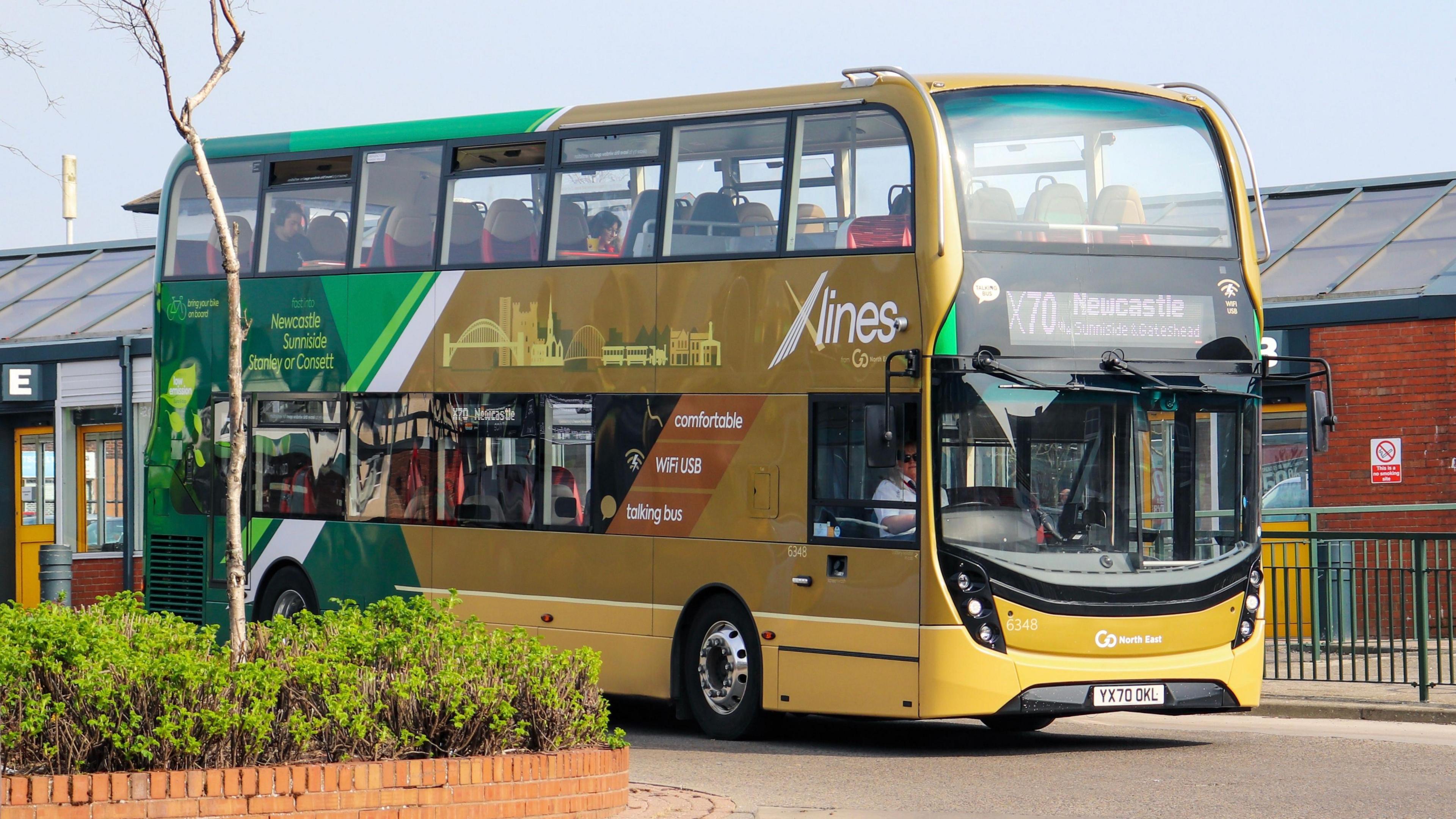 The yellow and green double decker X70 bus to Newcastle leaving a bus station