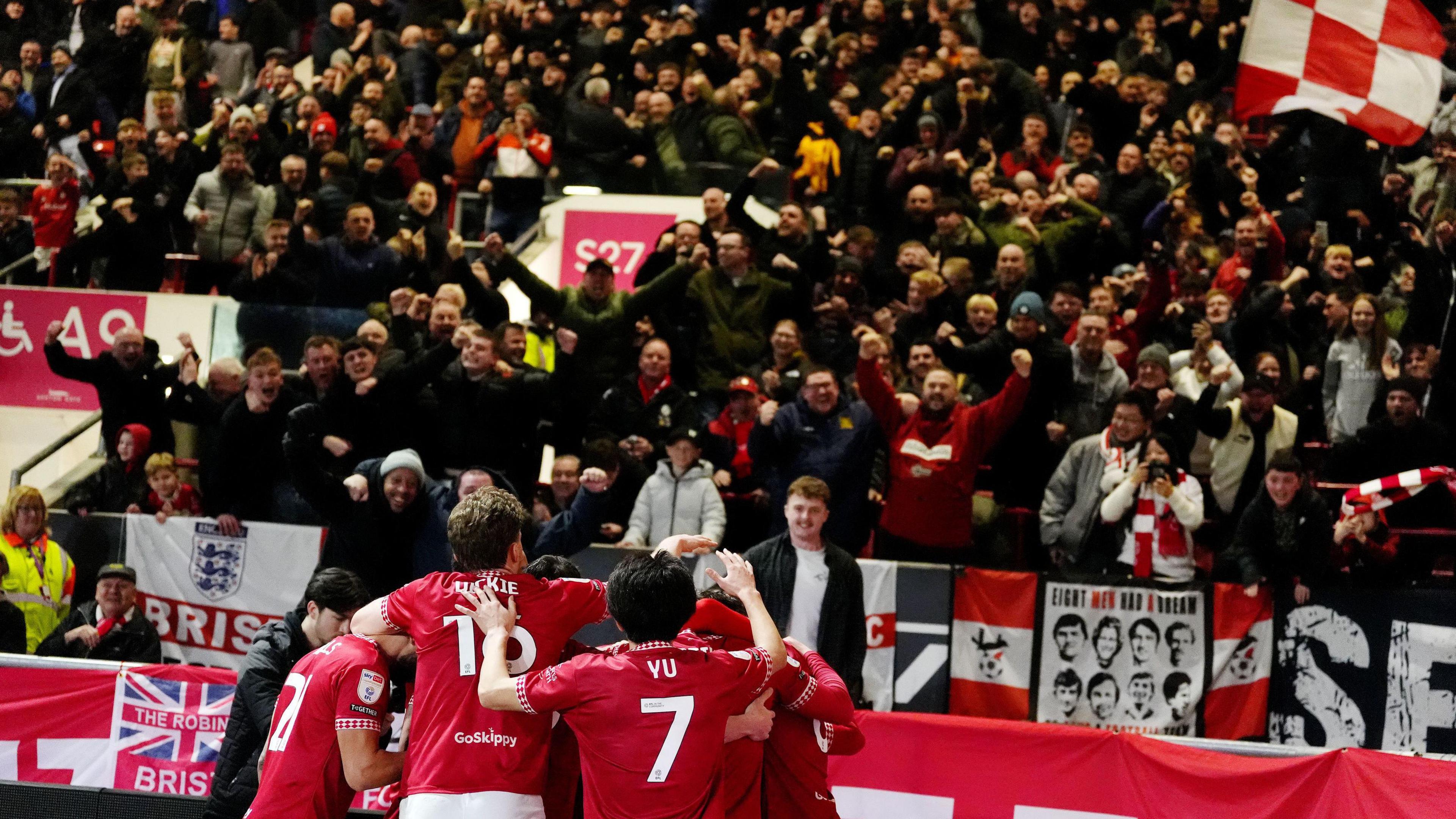 Bristol City players celebrate a goal against Middlesbrough while in the background hundreds of fans celebrate in the stands