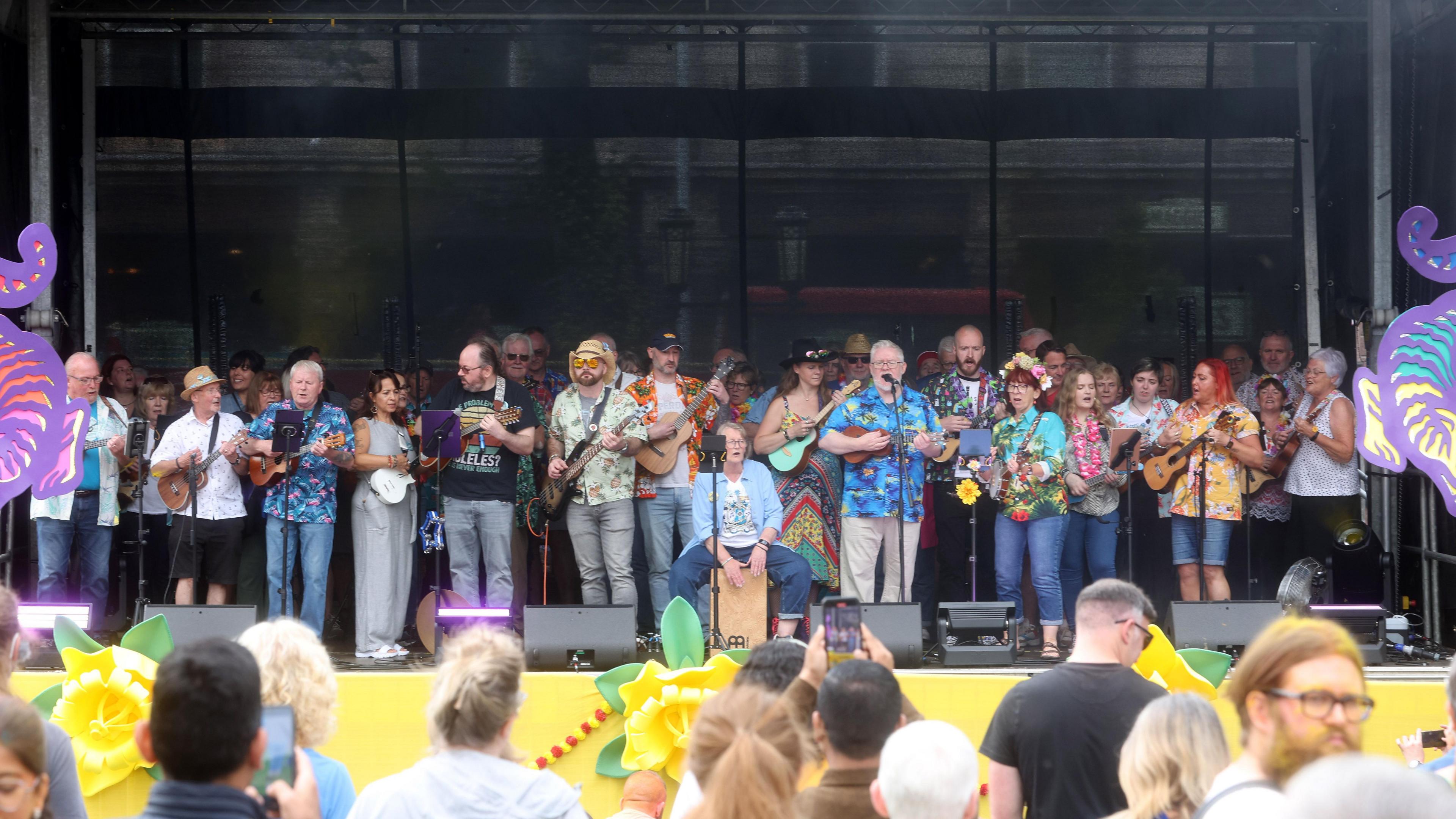 An act is performing on a stage. There is a large group of people holding instruments. 