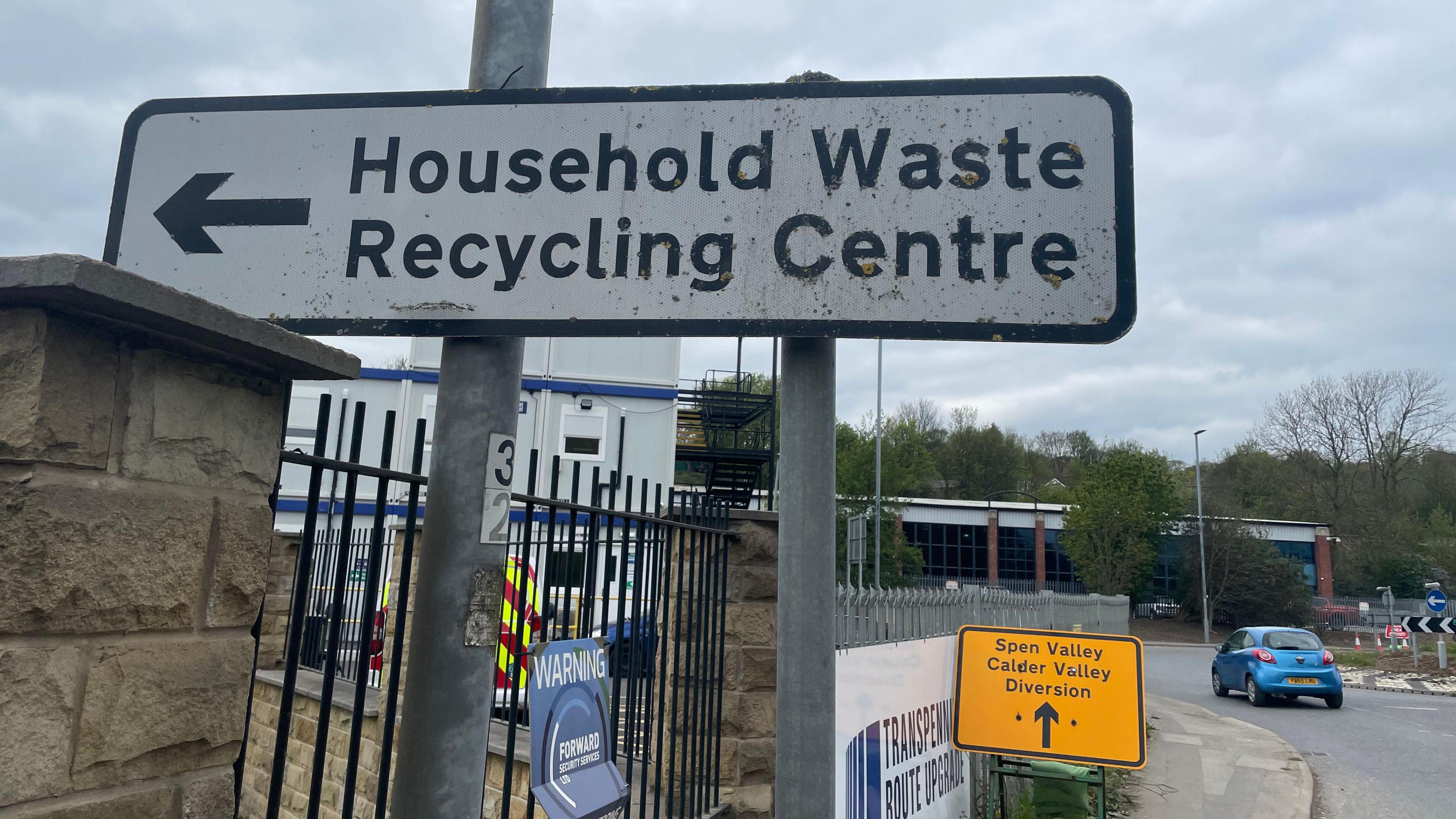 A road sign pointing to 'household waste recycling centre'