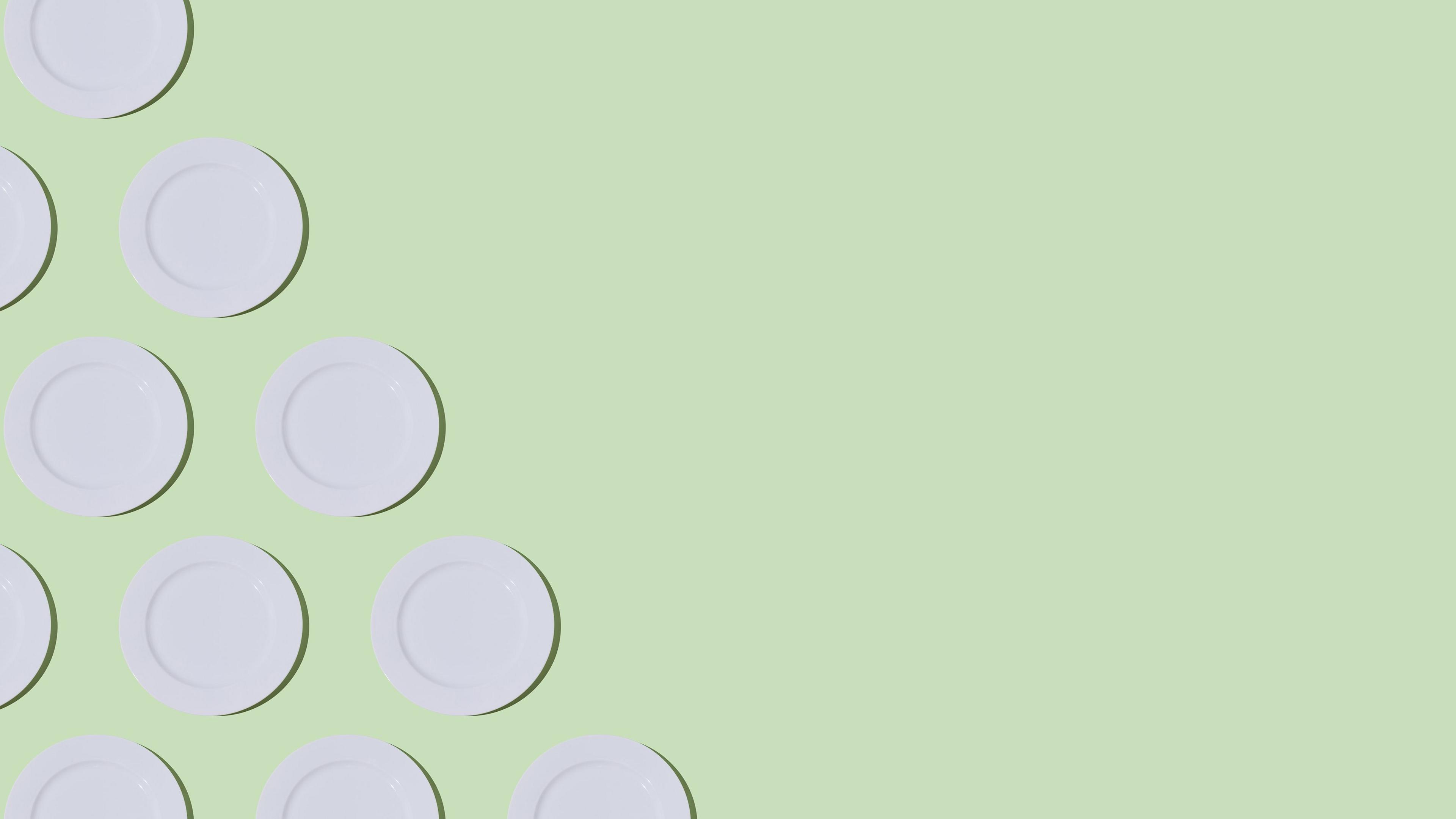 White dinner plates arranged in diagonal lines on a mint green background