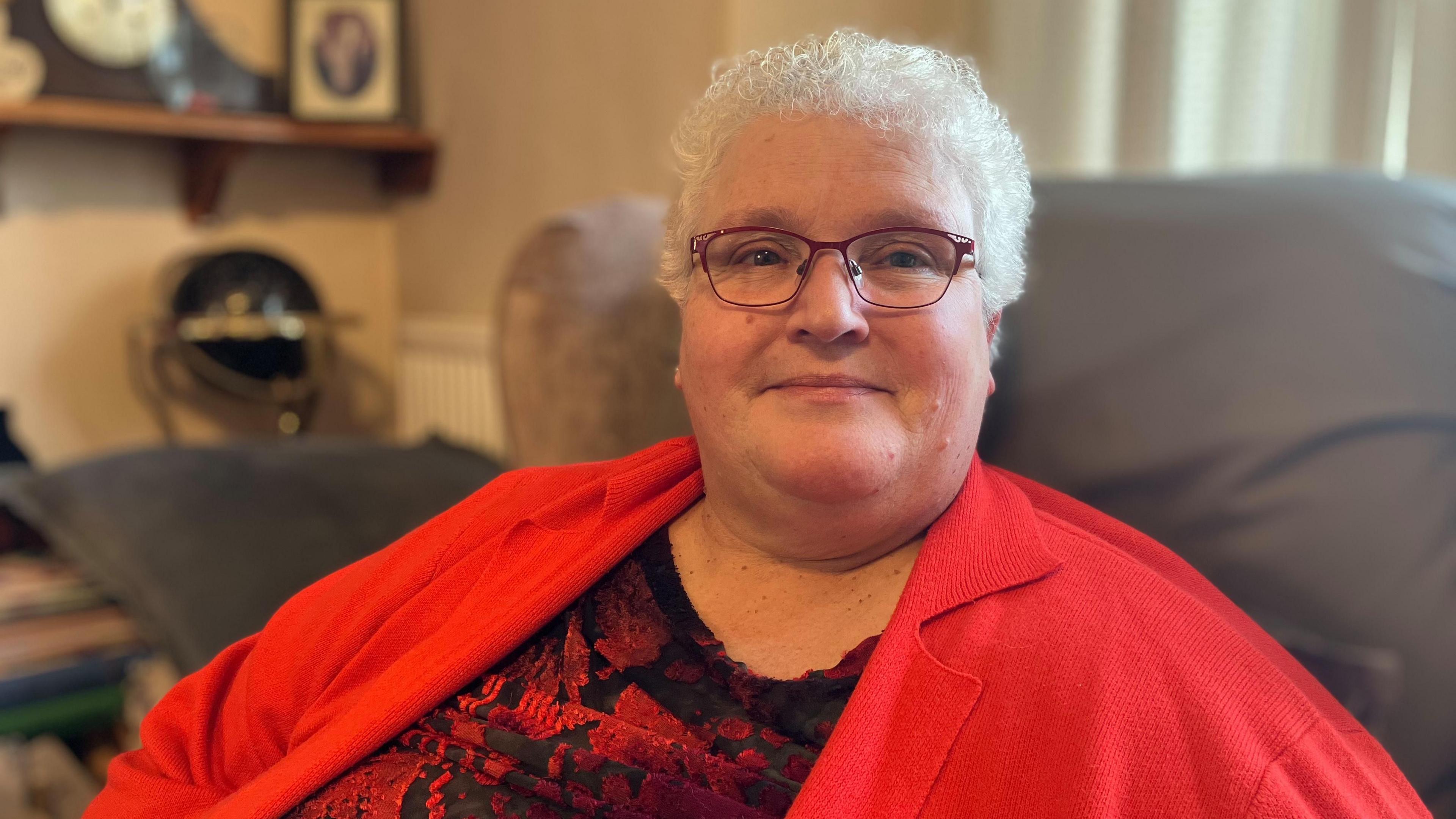 a woman in a red cardigan sitting in an armchair