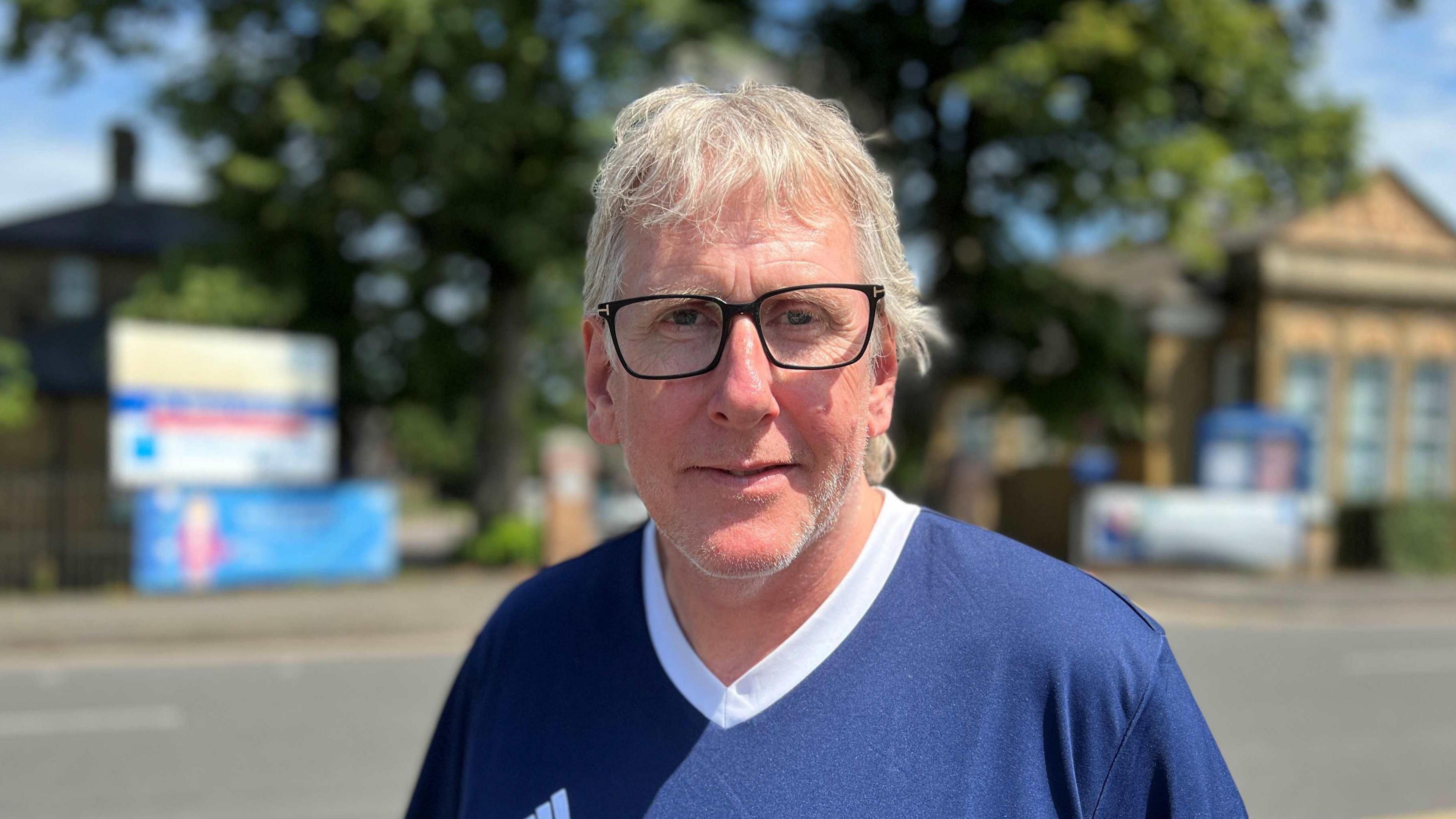 Jason Andrew wearing black framed glasses with a blue t-shirt