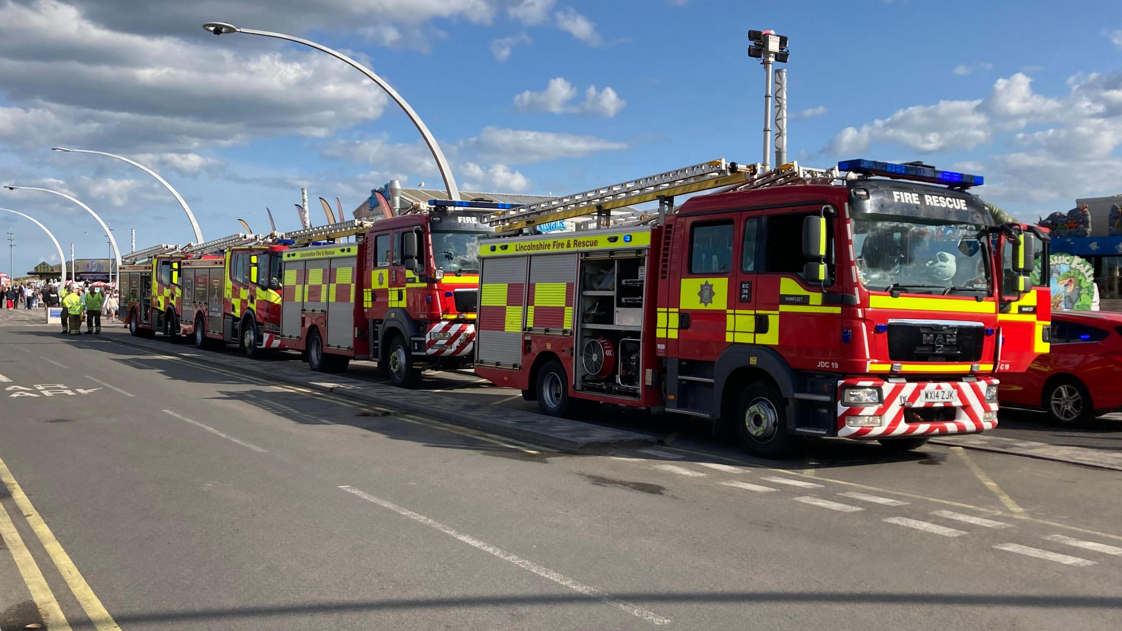 Fire crews parked on road outside attraction with people in view