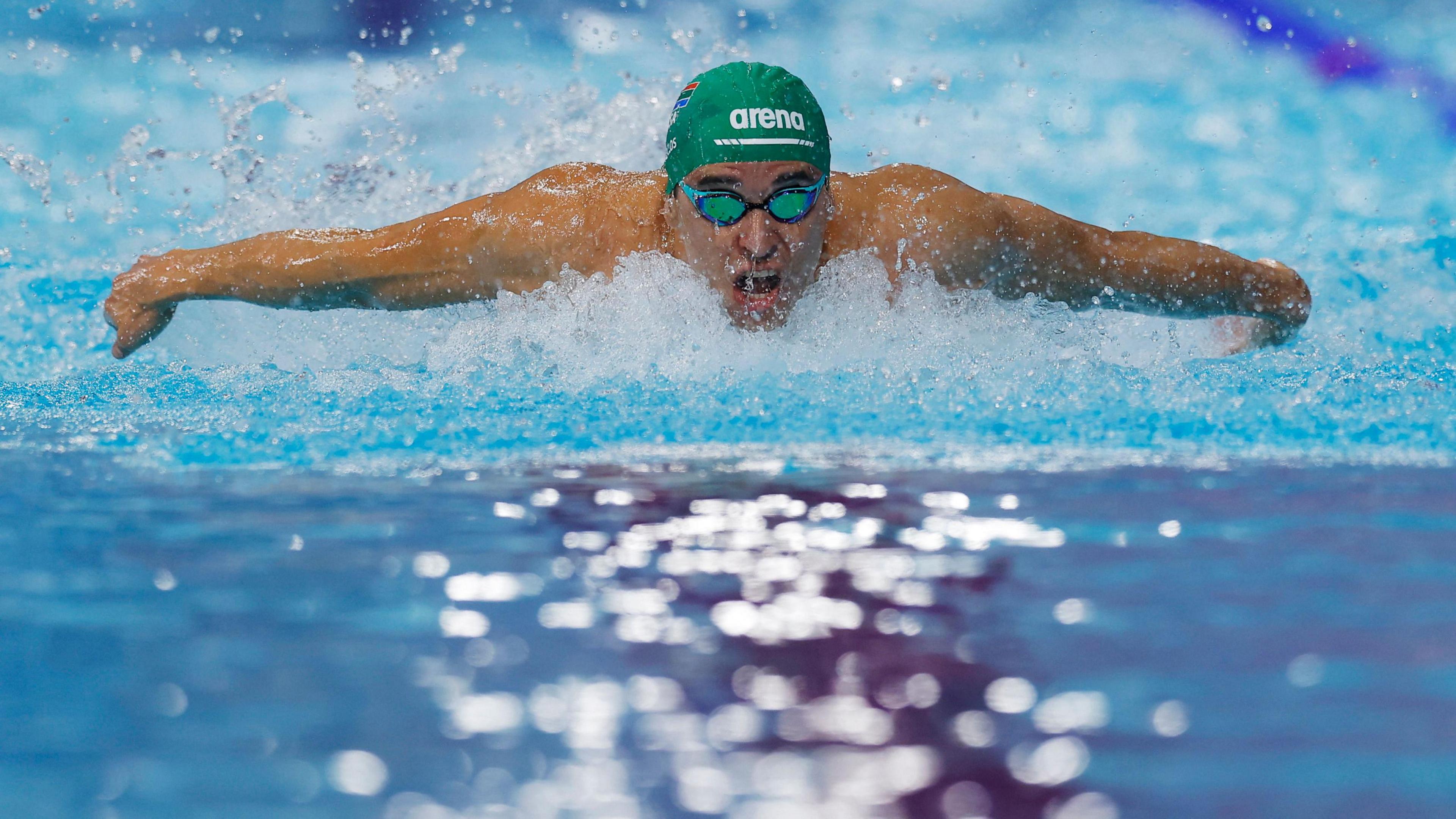 Chad le Clos doing the butterfly stroke in the pool while wearing a green swimming cap