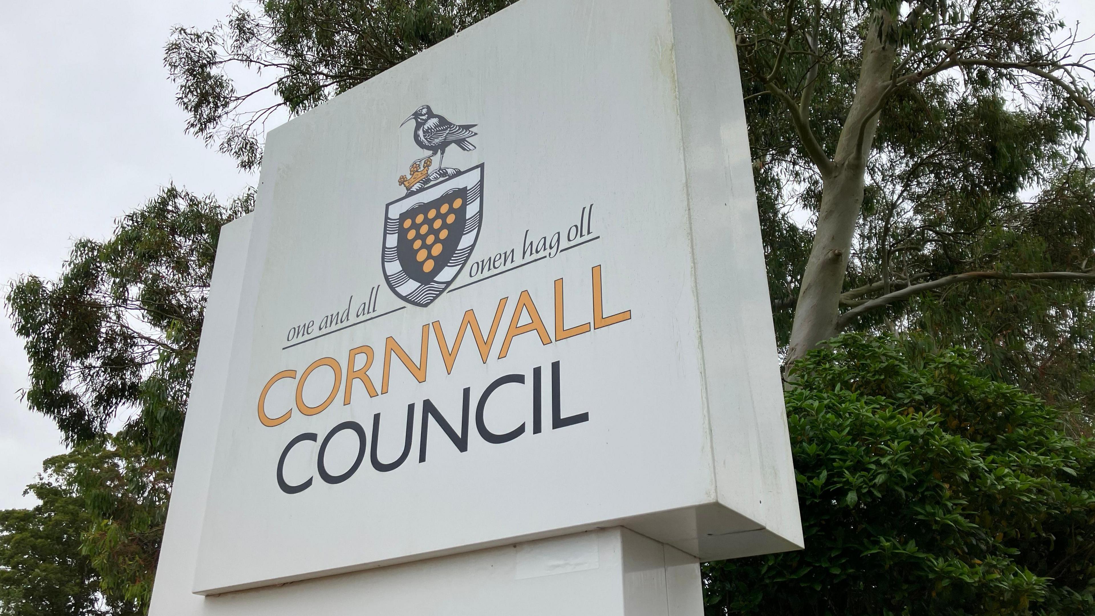 A picture the Cornwall Council logo outside one of the offices. In the background, there are trees.