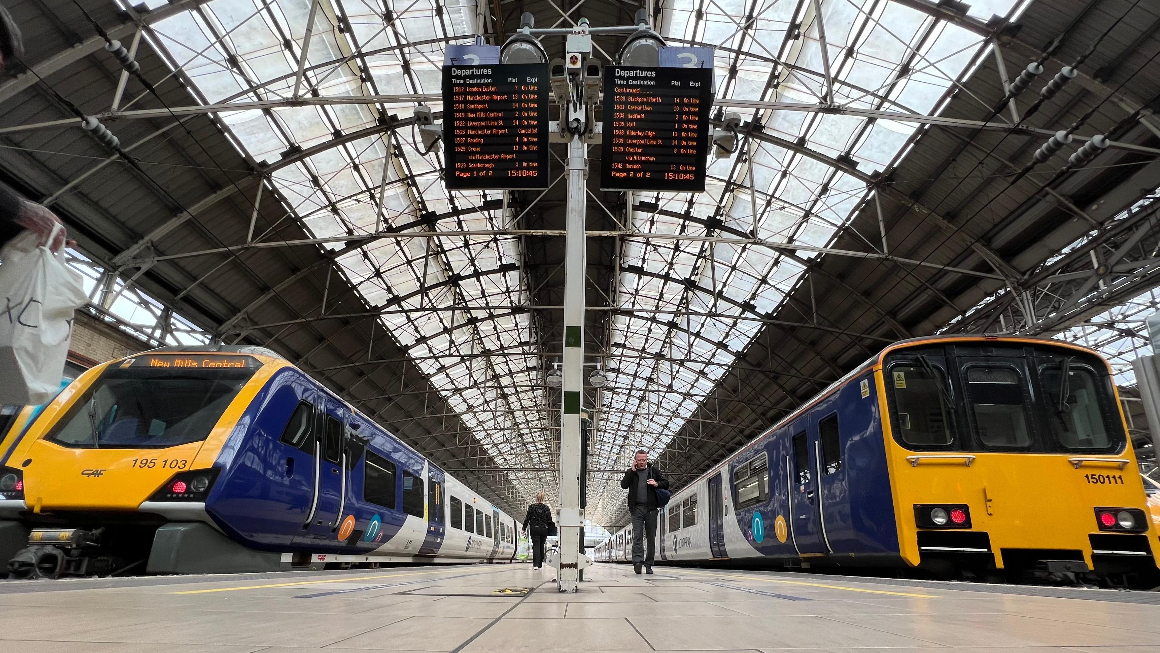 two trains on platforms under the glass roof at Manchester Piccadilly