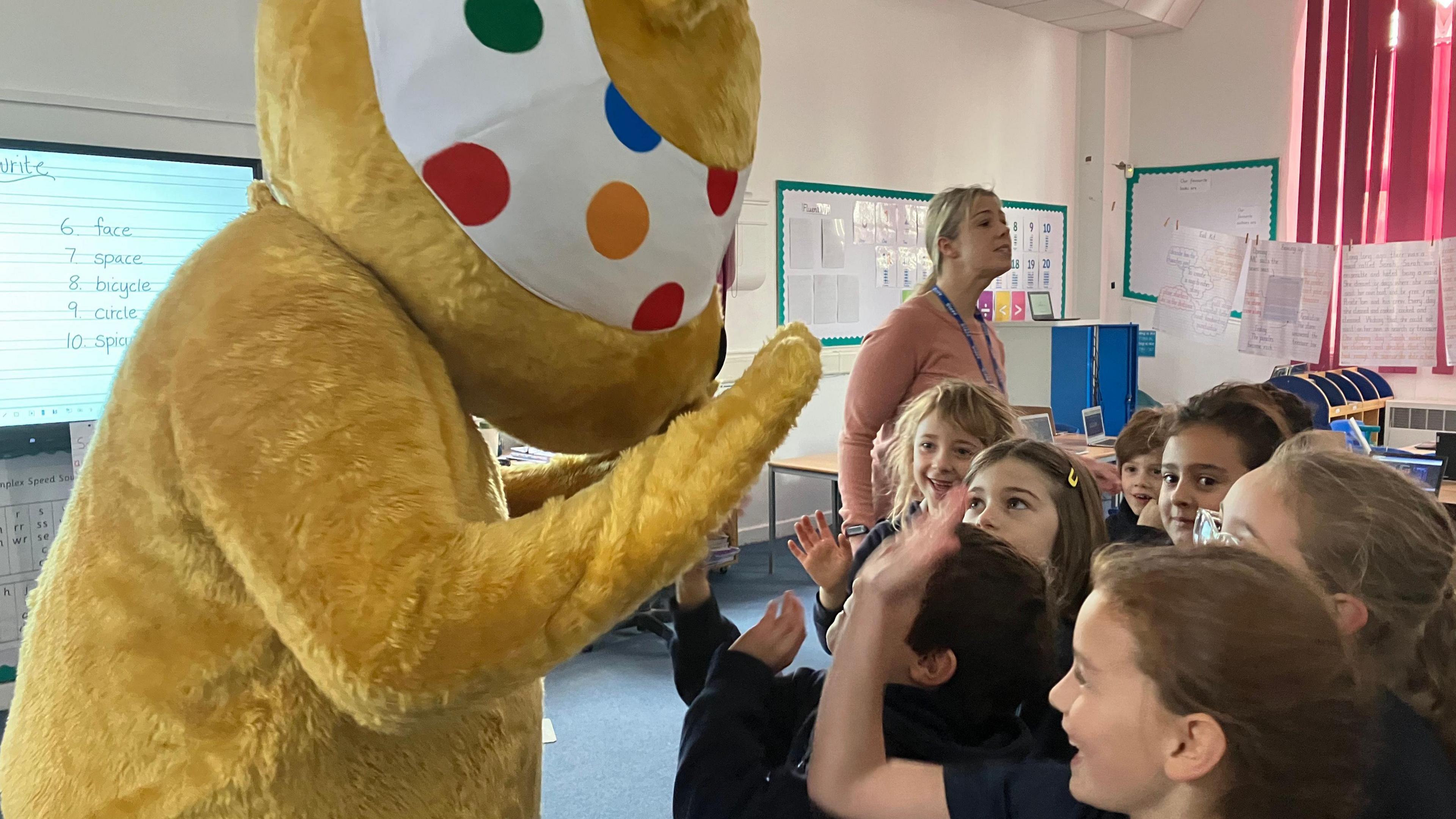 Pudsey bear high fives primary school children 