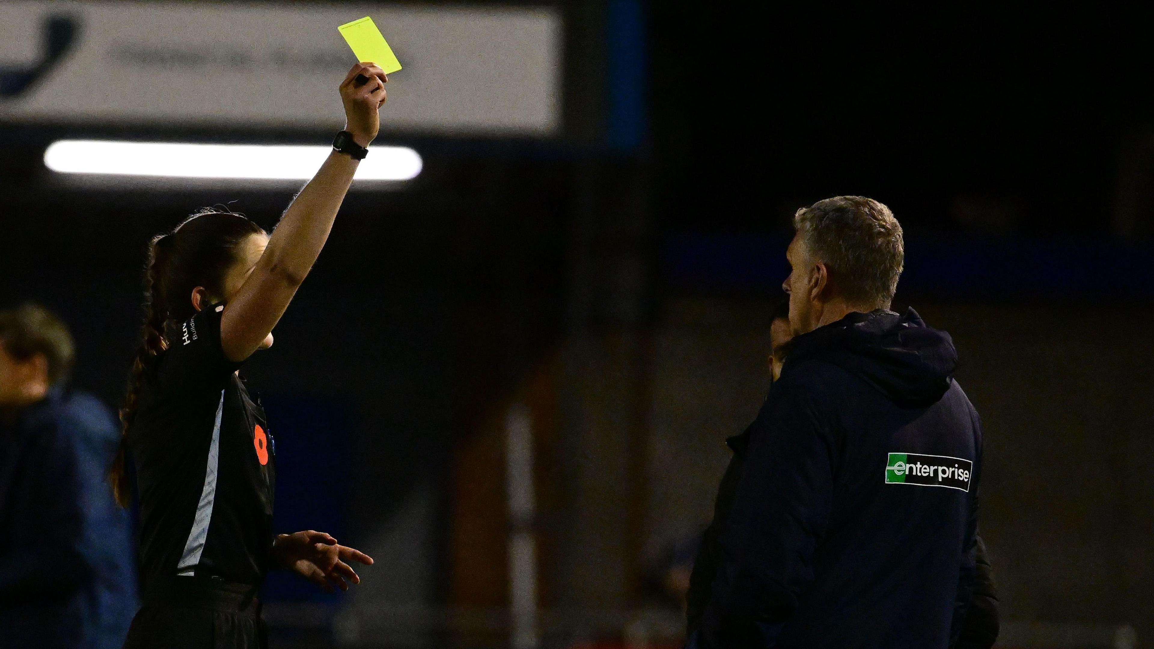 John Askey is booked for his reaction to Donnellan's sending off