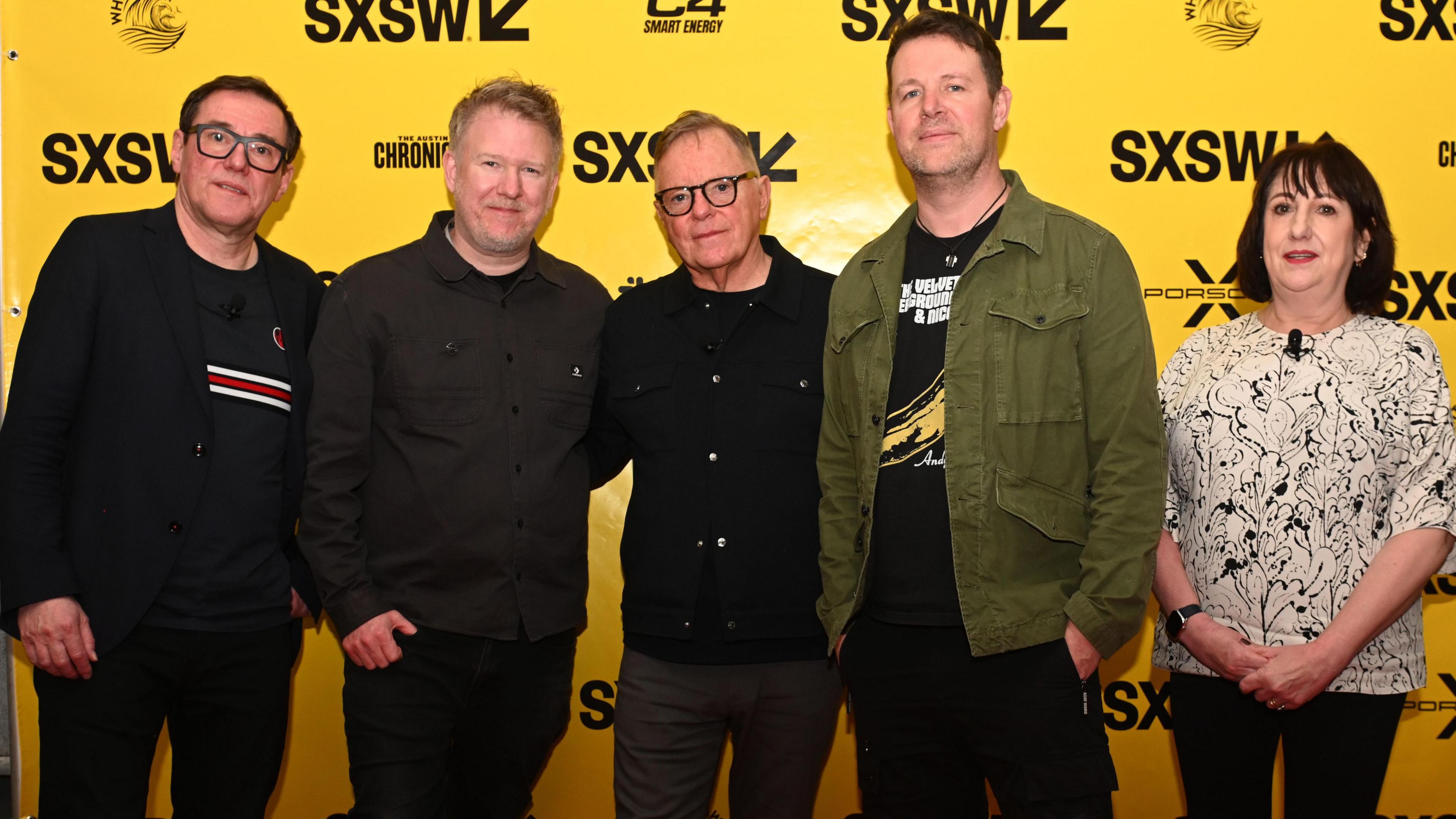 Five members of New Order band smiling at the camera 