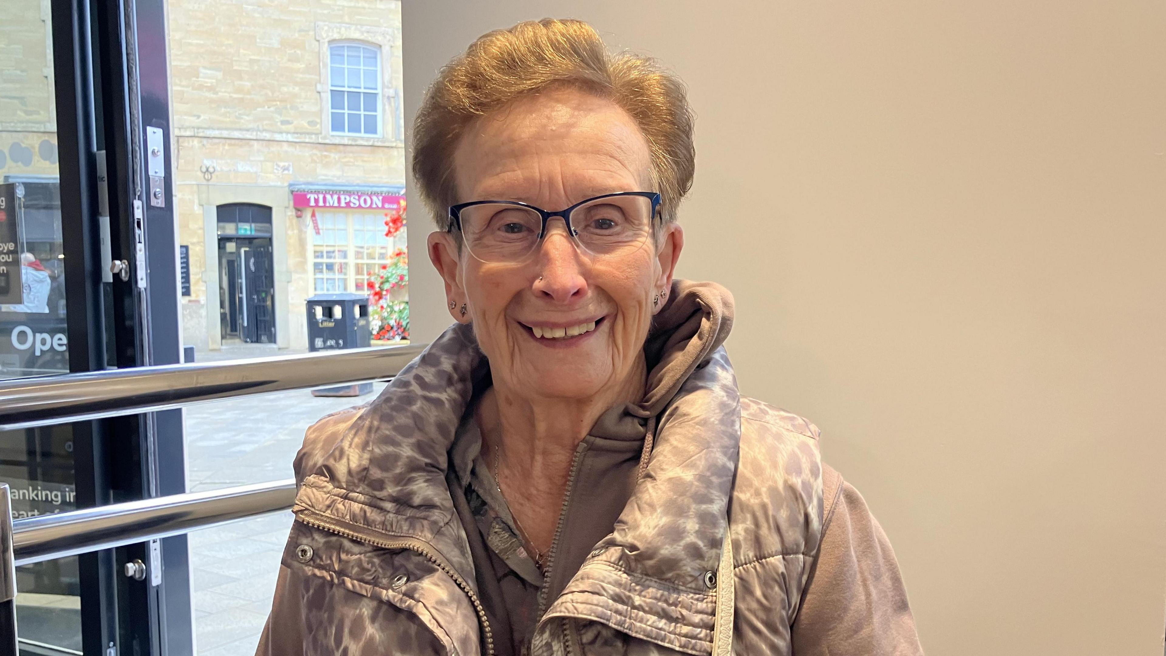 A woman with short brown hair and glasses smiling at the camera.