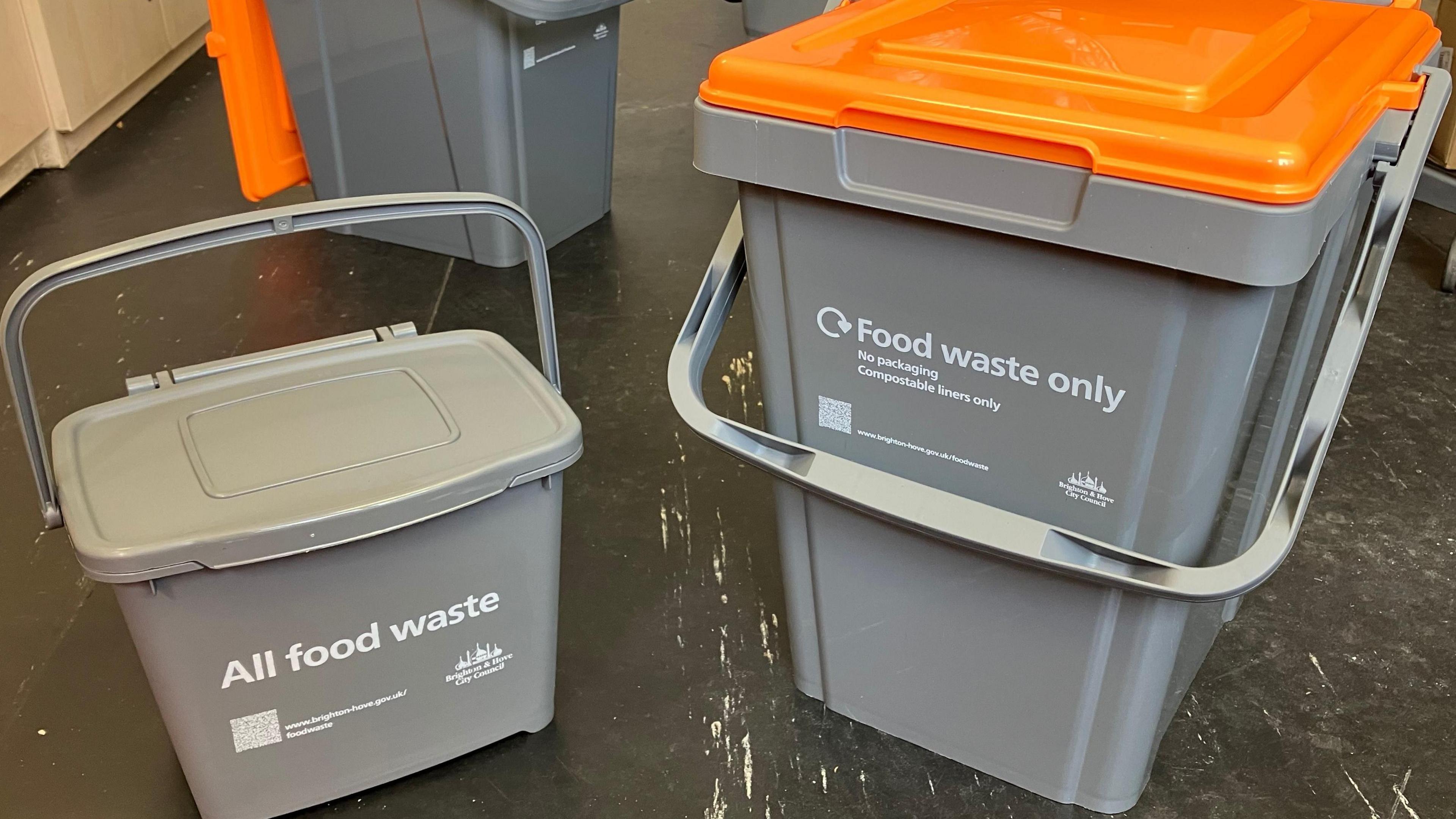 A small and large grey plastic food waste collection bin in Brighton & Hove, the large one with an orange lid.