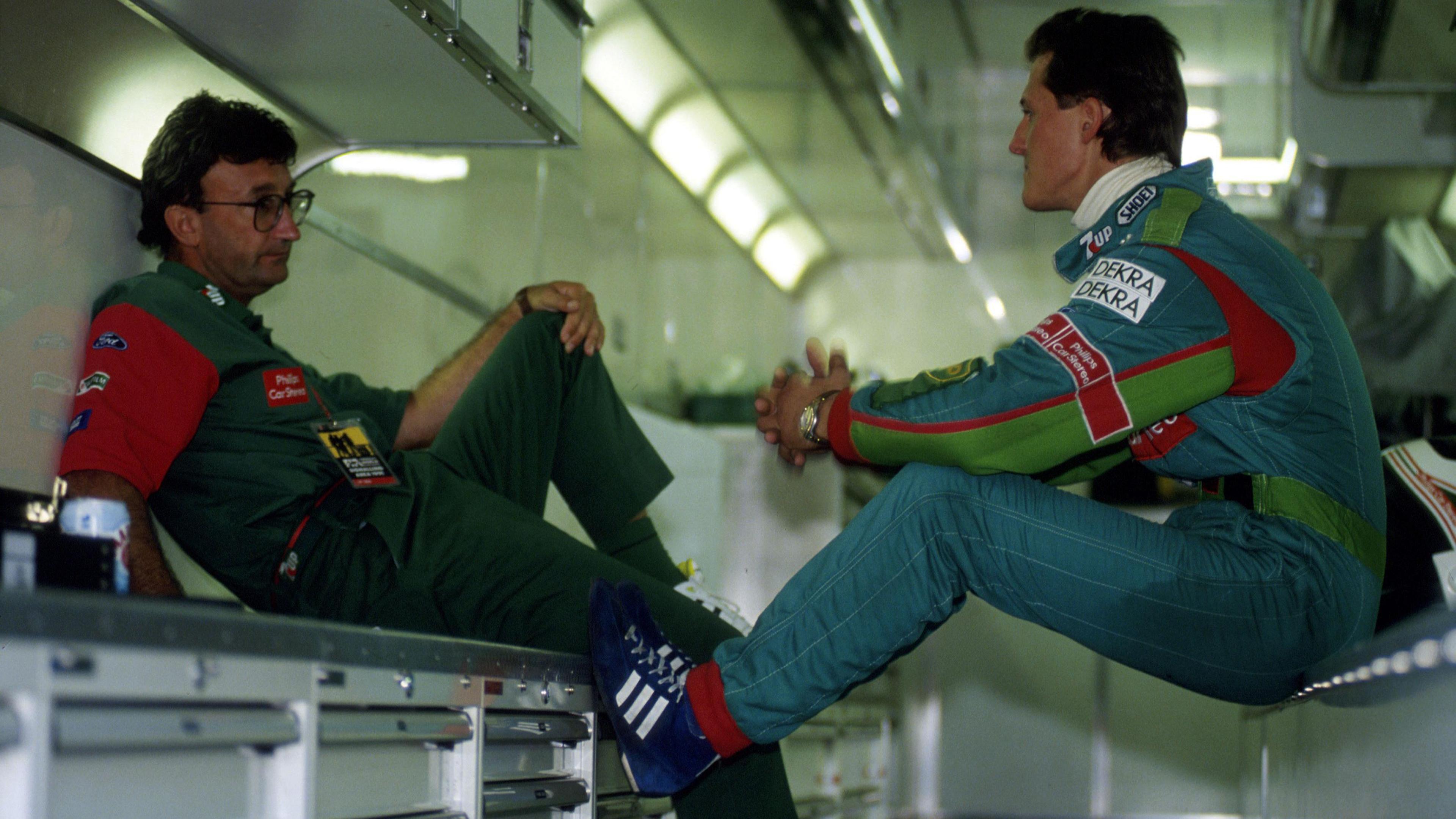 Eddie Jordan sits down while speaking to Michael Schumacher in the Jordan team garage at the 1991 Belgian Grand Prix