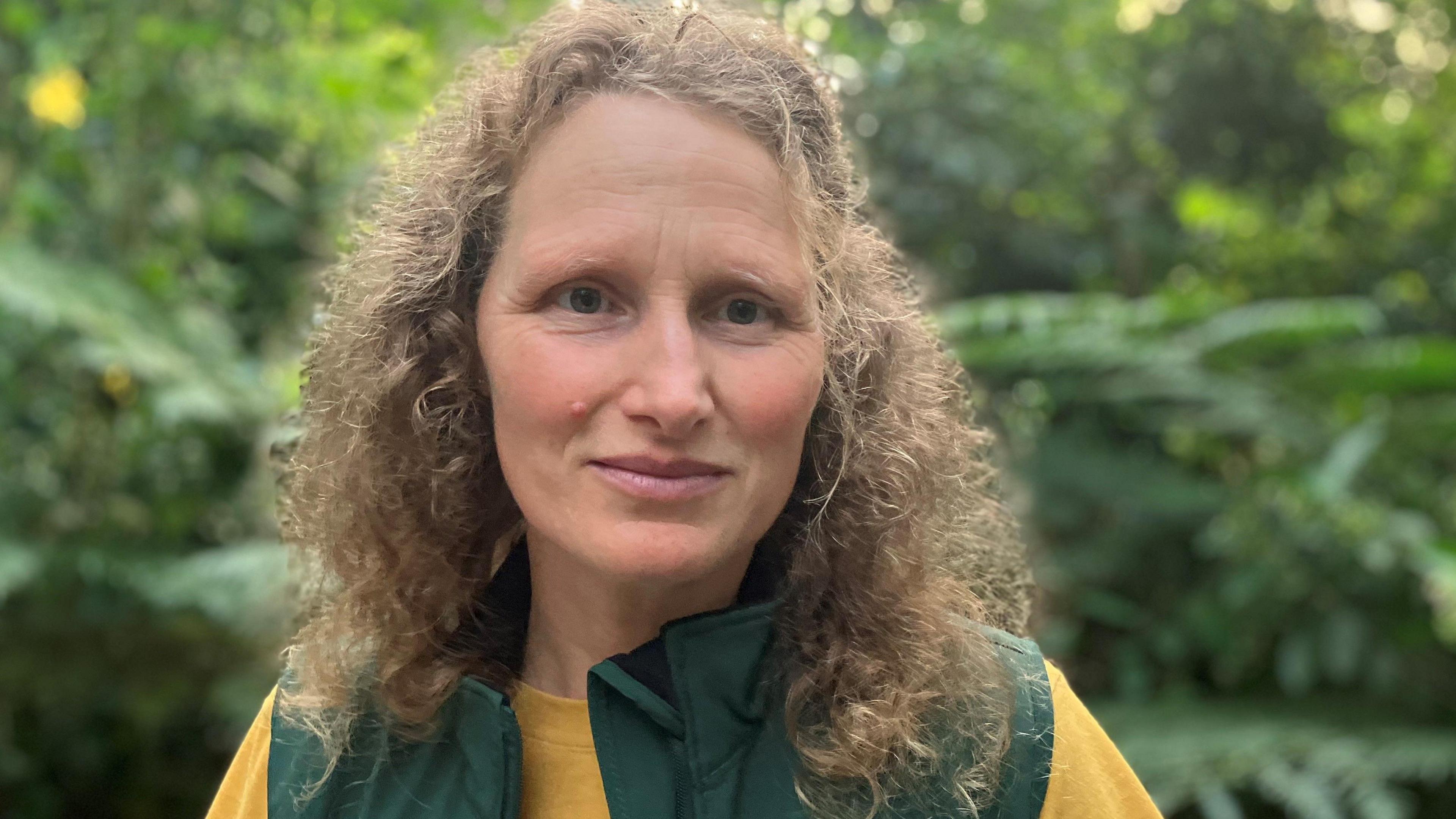 Woman with curly hair with a backdrop of plants in the rainforest biome