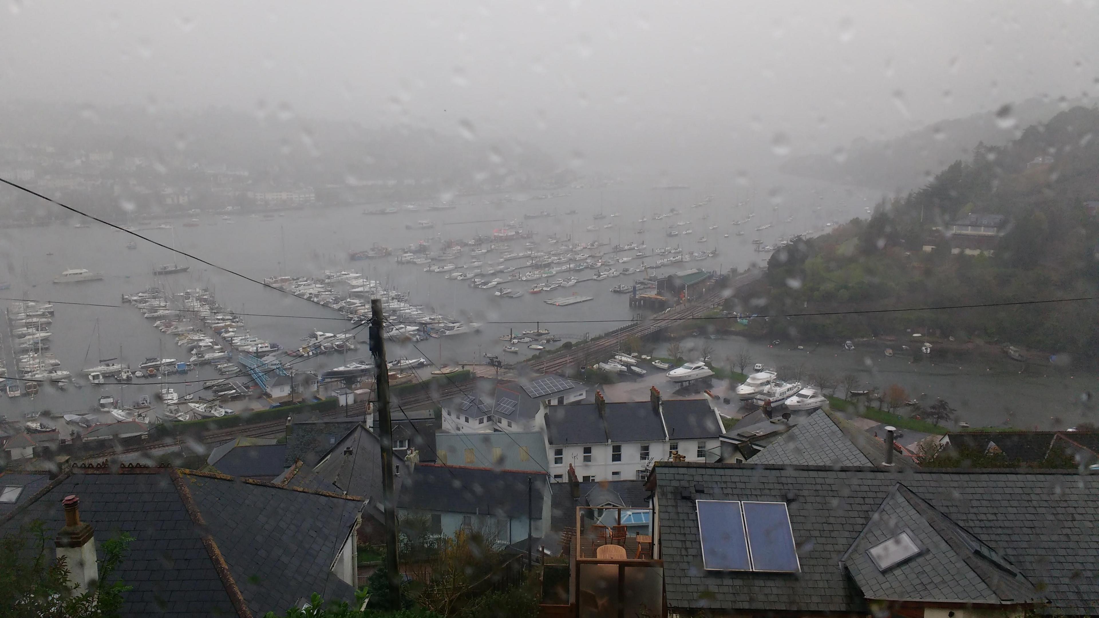 Rain falls in Kingswear, Devon. Low mist is over the village.