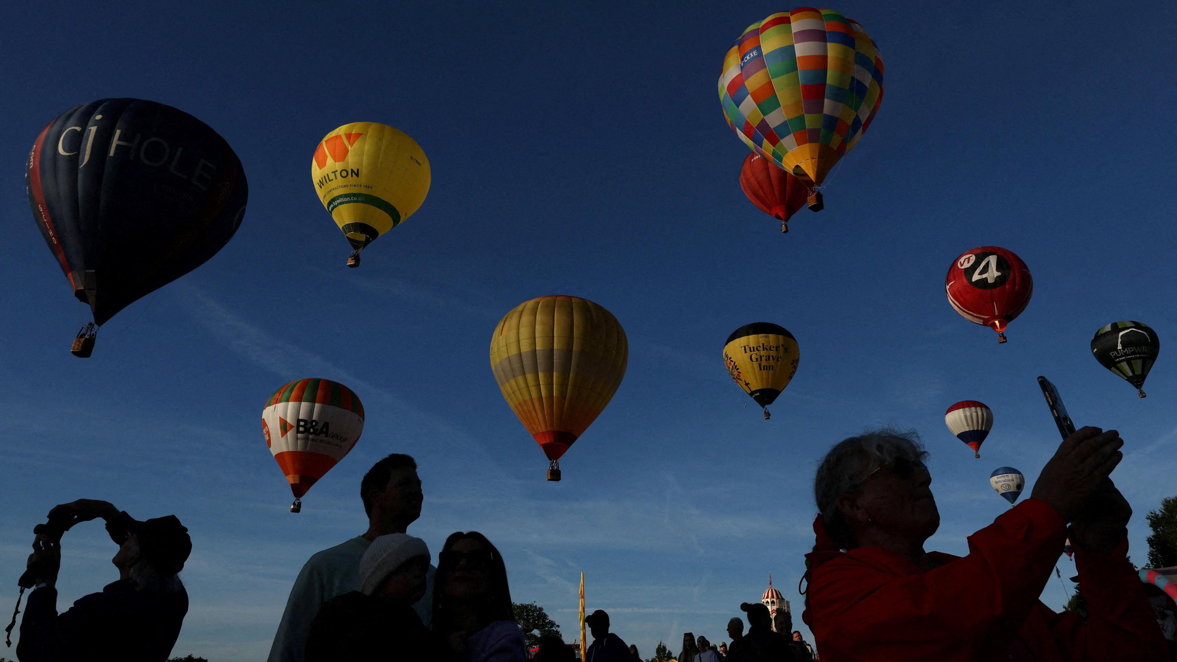 People take selfies as the balloons ascend above them