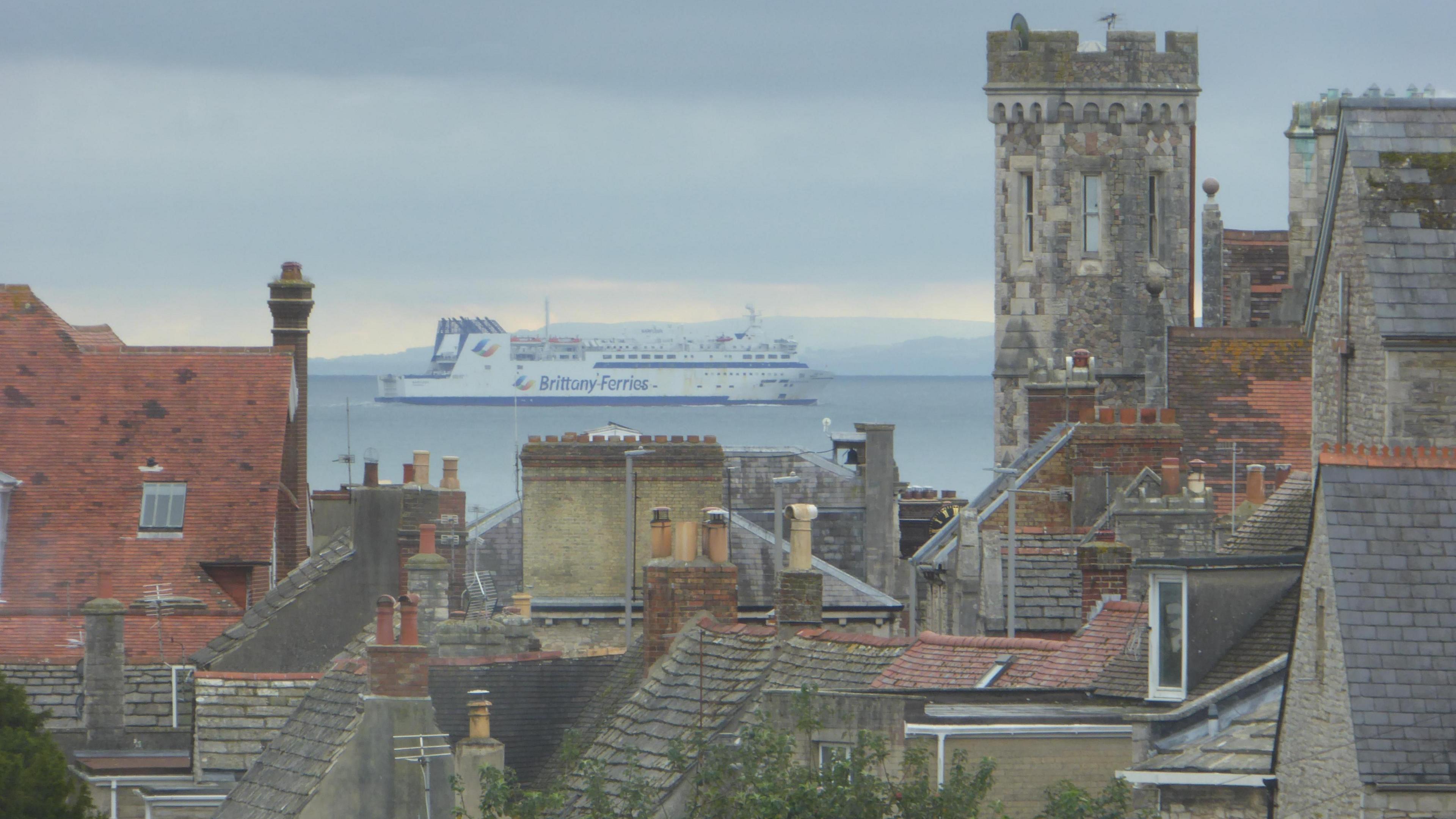 The Brittany Ferries passenger ferry can be seen in Poole Harbour, with a number of building tops in Purbeck in the foreground