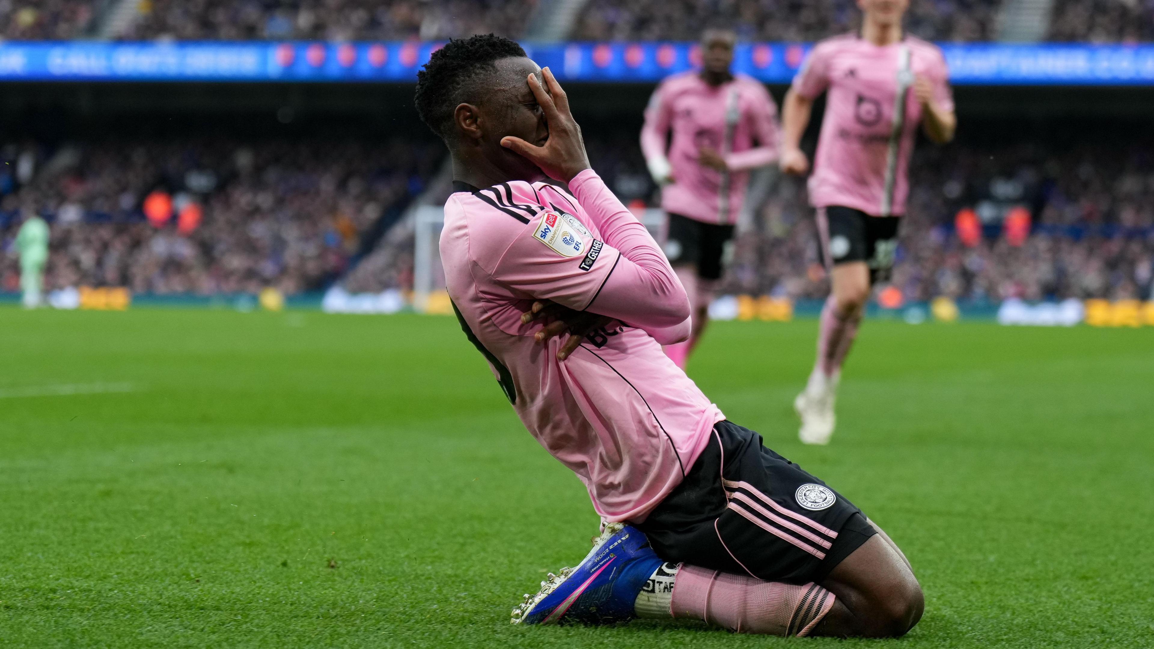 Leicester City striker Patson Daka celebrates on his knees with hands over his face in pink and black away kit