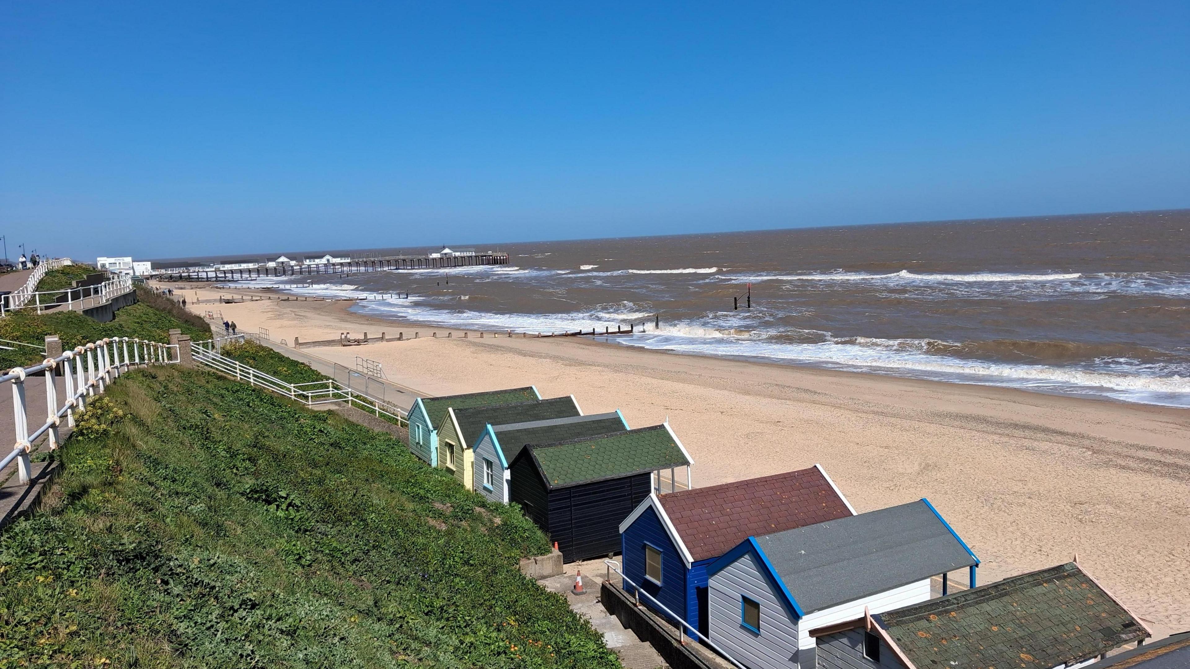 Beach huts in the foreground on Southwold beach with blue sky and sunshine