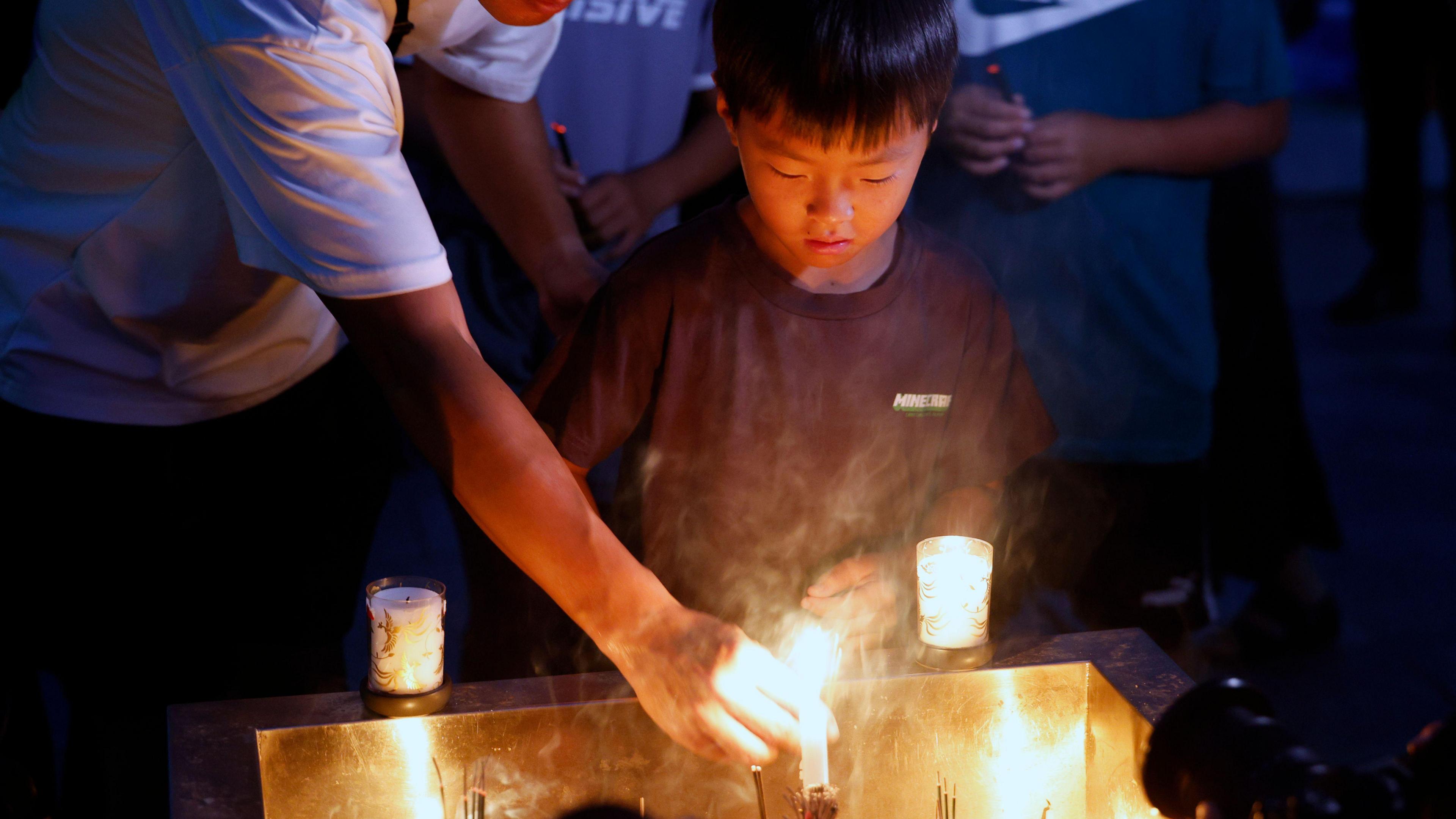 A boy lights incense at the at the Peace Memorial Park in Hiroshima on the 80th Atomic Bombing Day anniversary in Hiroshima, western Japan