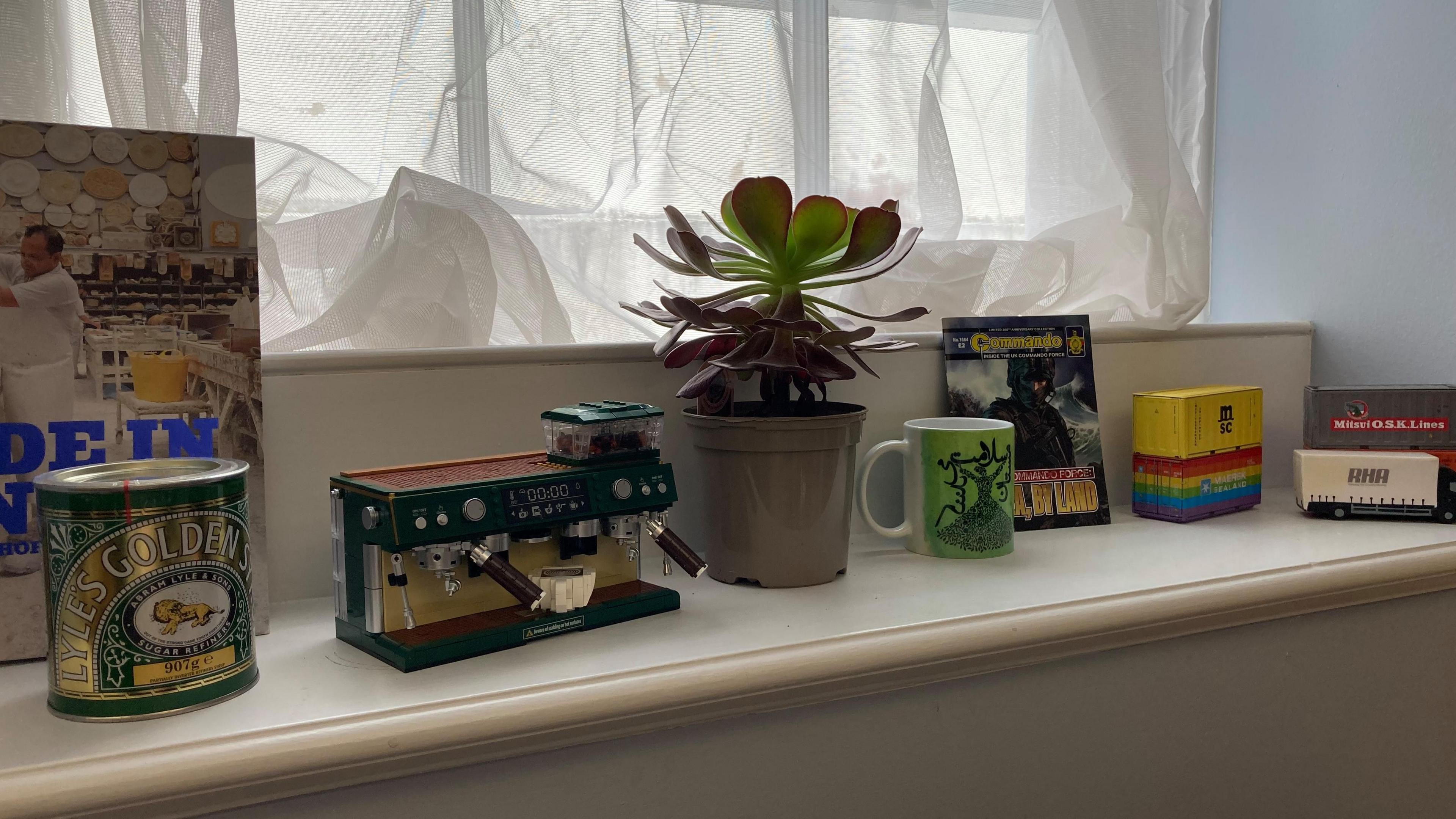 A green mug, a tin of lyle's golden syrup, commando comic, a couple of logistics trucks