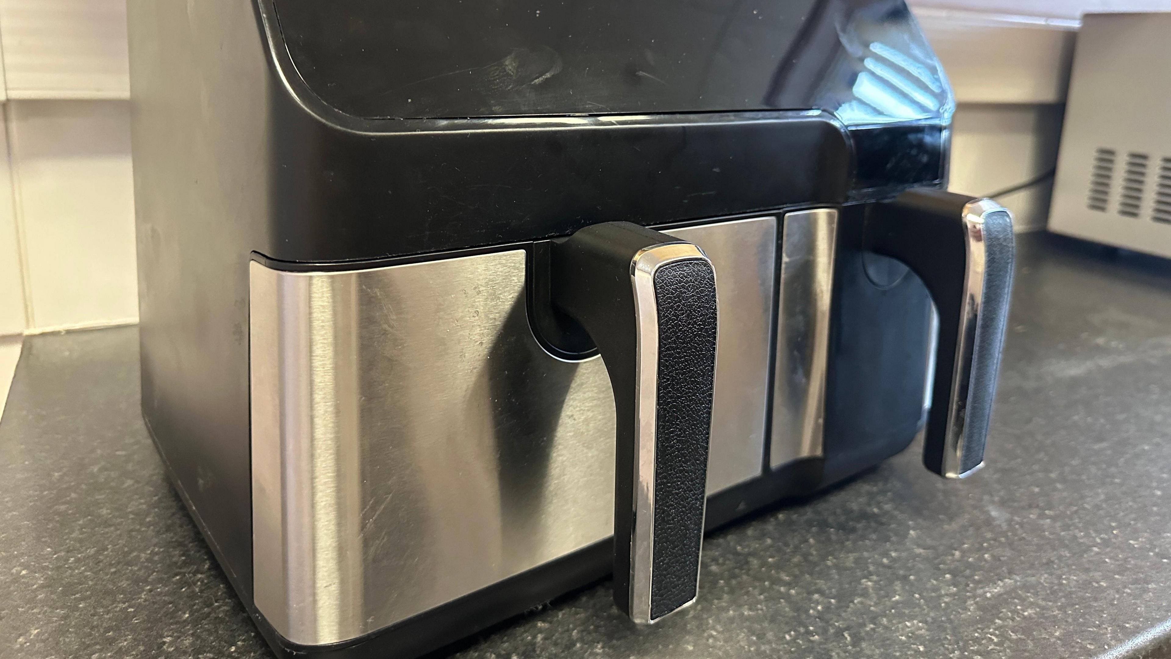 An air fryer with two closed baskets on a kitchen worktop.