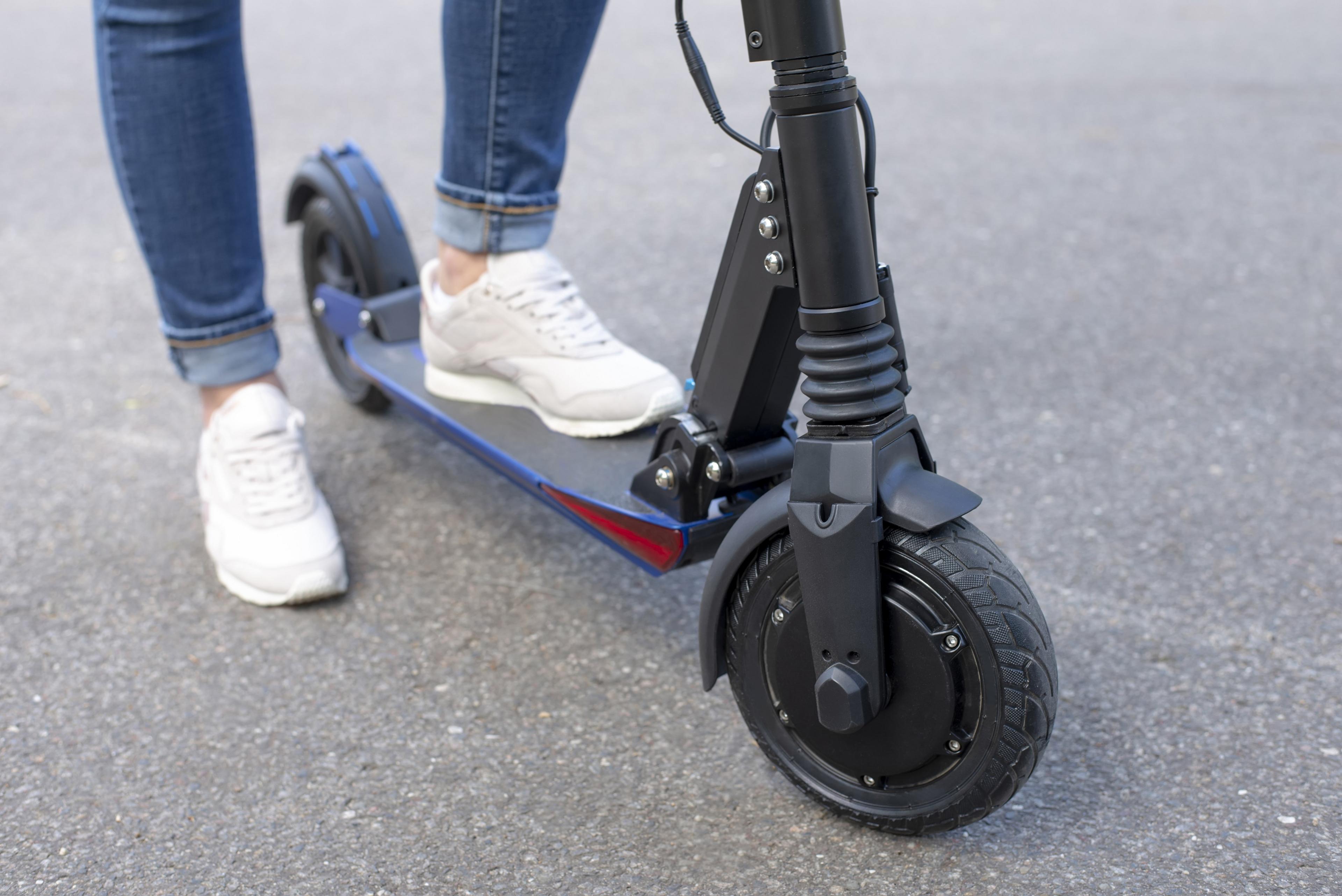 Close up of e-scooter with feet on the scooter.