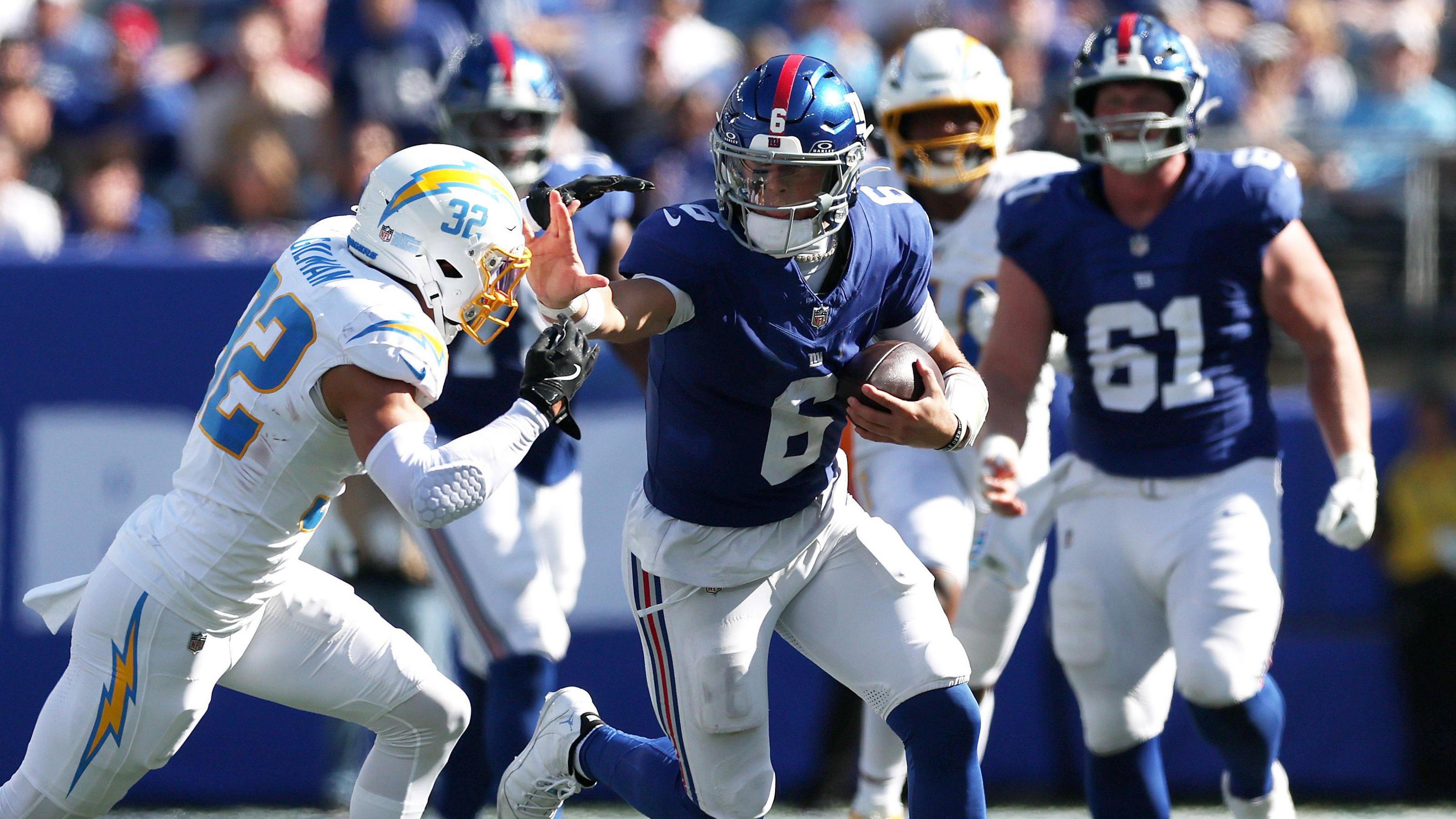 Jaxson Dart of the New York Giants pushes off a Los Angeles Chargers defence during his NFL debut at MetLife Stadium