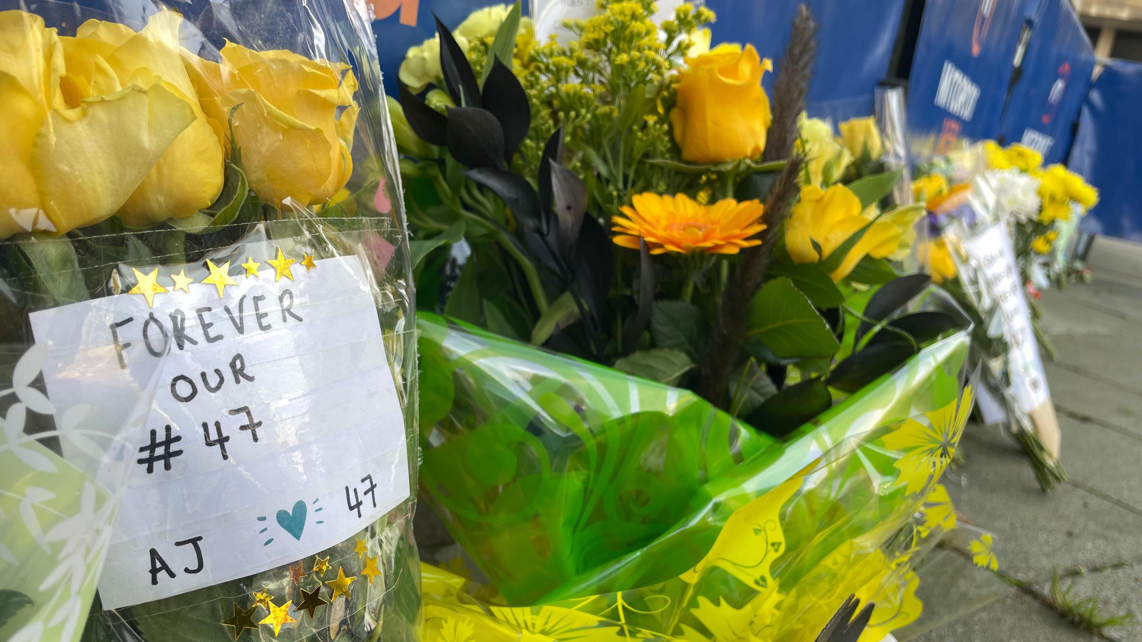 A bouquet of yellow flowers with a piece of paper saying "forever our 47" 